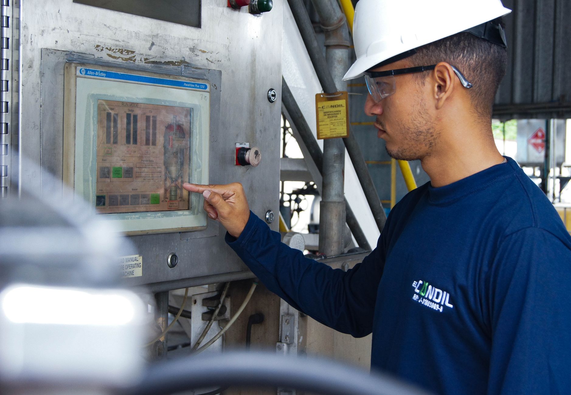 A worker's hand touches an icon on a large, intuitive touchscreen on a piece of factory machinery, symbolizing the ease of use of modern cobots.