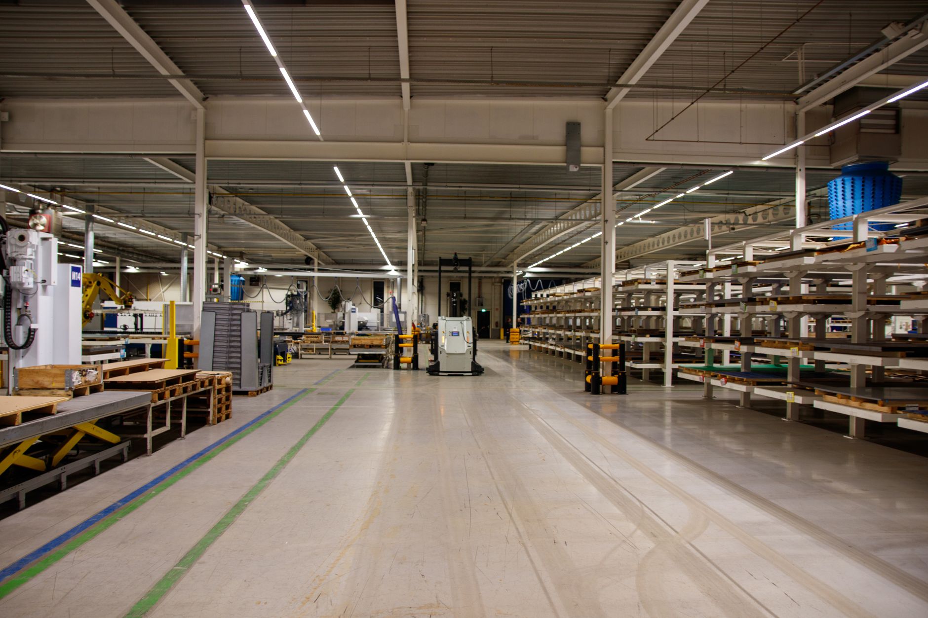 A wide, empty aisle in a modern warehouse, representing the clear pathways used by autonomous mobile robots to transport materials safely.