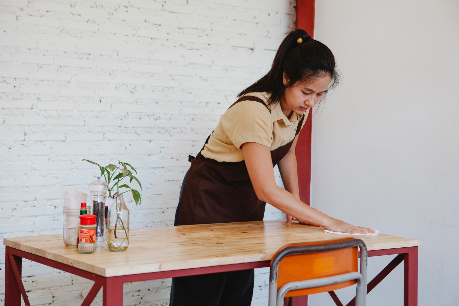 A uniformed cleaning staff member meticulously wipes down a high-touch surface in a commercial building.