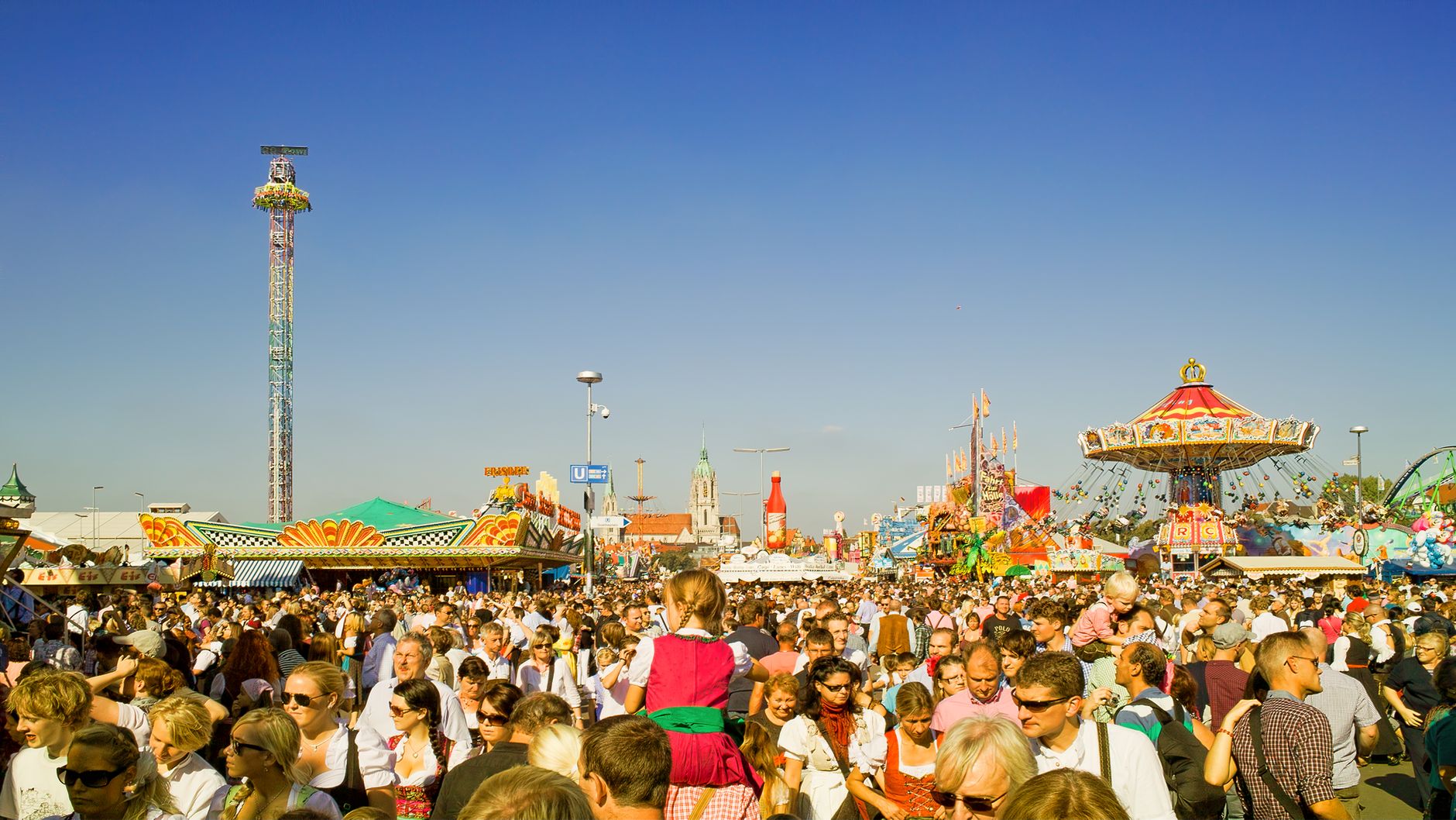 Visitors walking through a busy theme park plaza, illustrating the crowd density large venues manage when adding service automation.