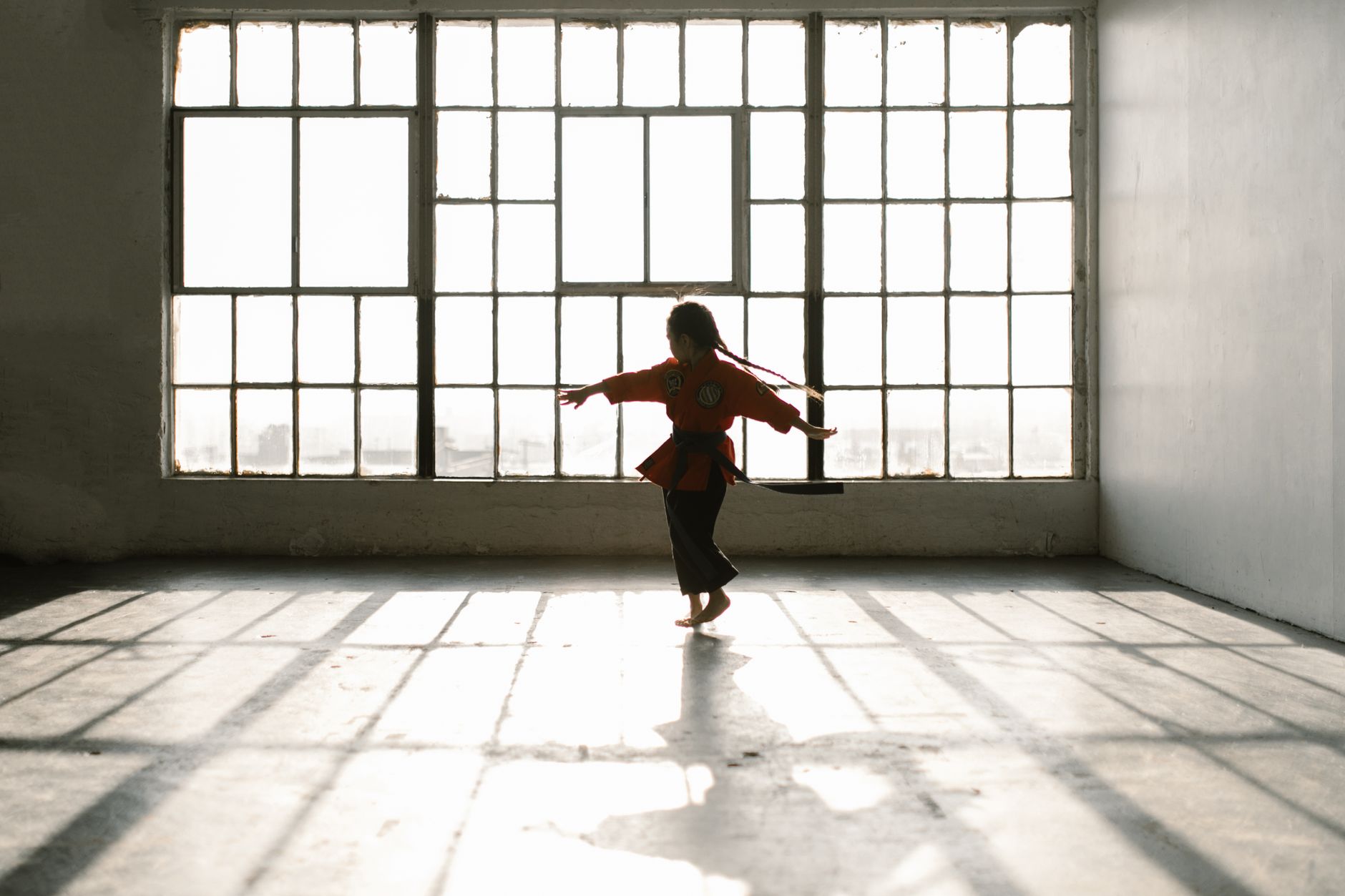 An empty martial arts studio with padded training mats and a visible hard-floor perimeter.