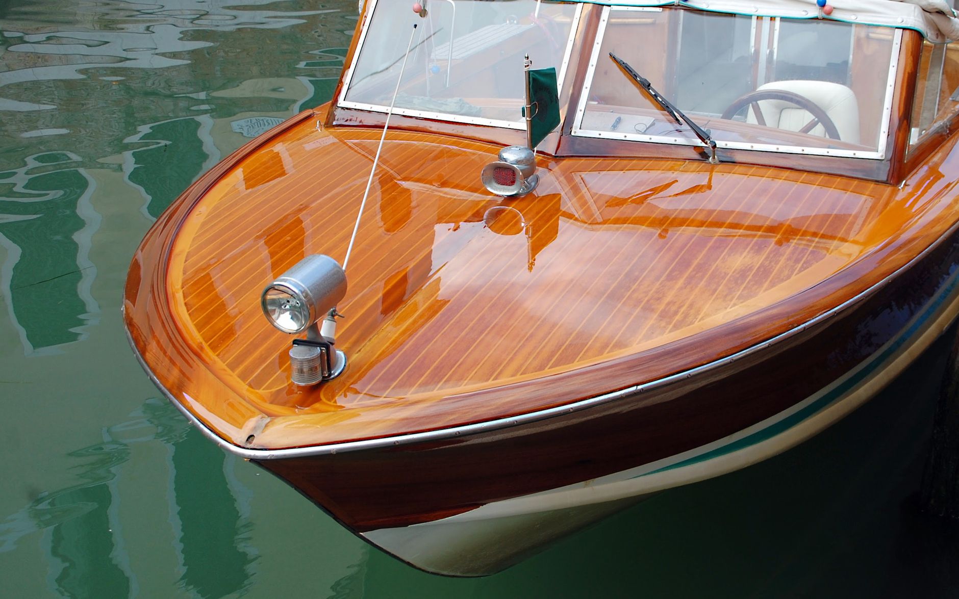 A marine finisher polishes the gelcoat surface of a boat hull inside a production facility.