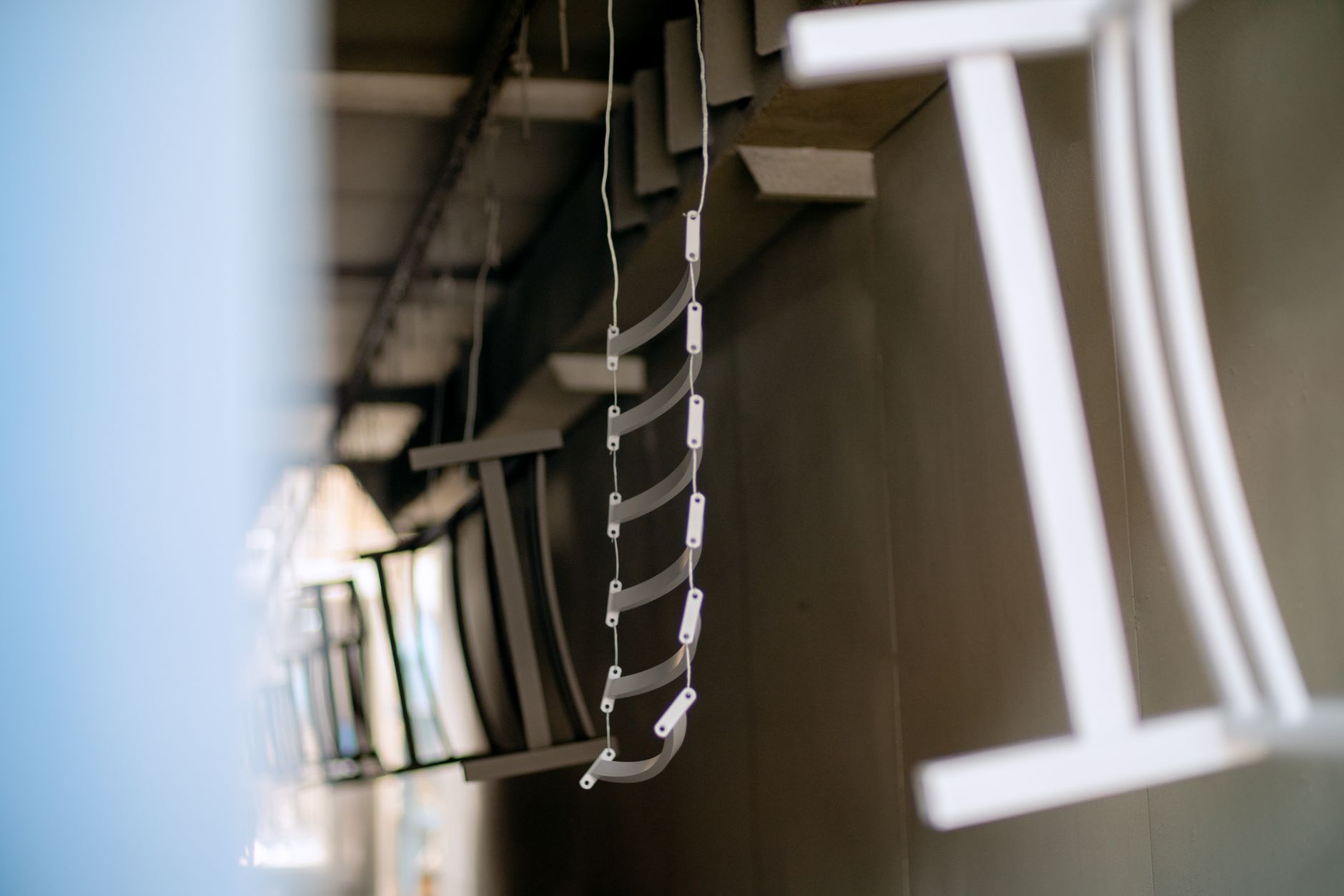 Metal parts hang at different heights and depths across an industrial finishing rack.