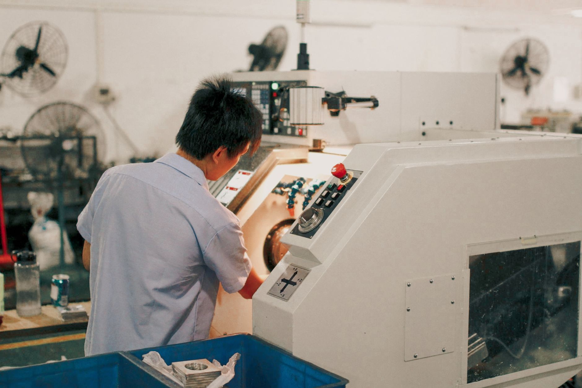 A fabrication worker tends a machining station where consistent part positioning can support repeatable production.