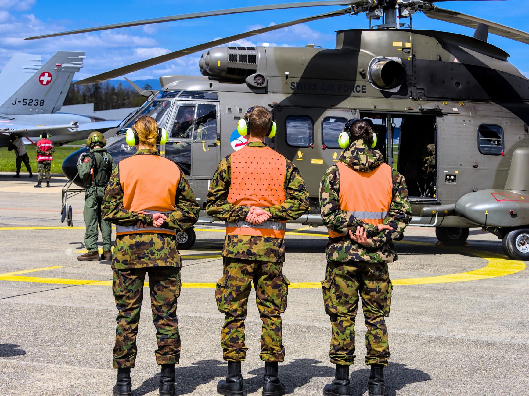Ground personnel coordinating beside a helicopter while maintaining a safe working distance.