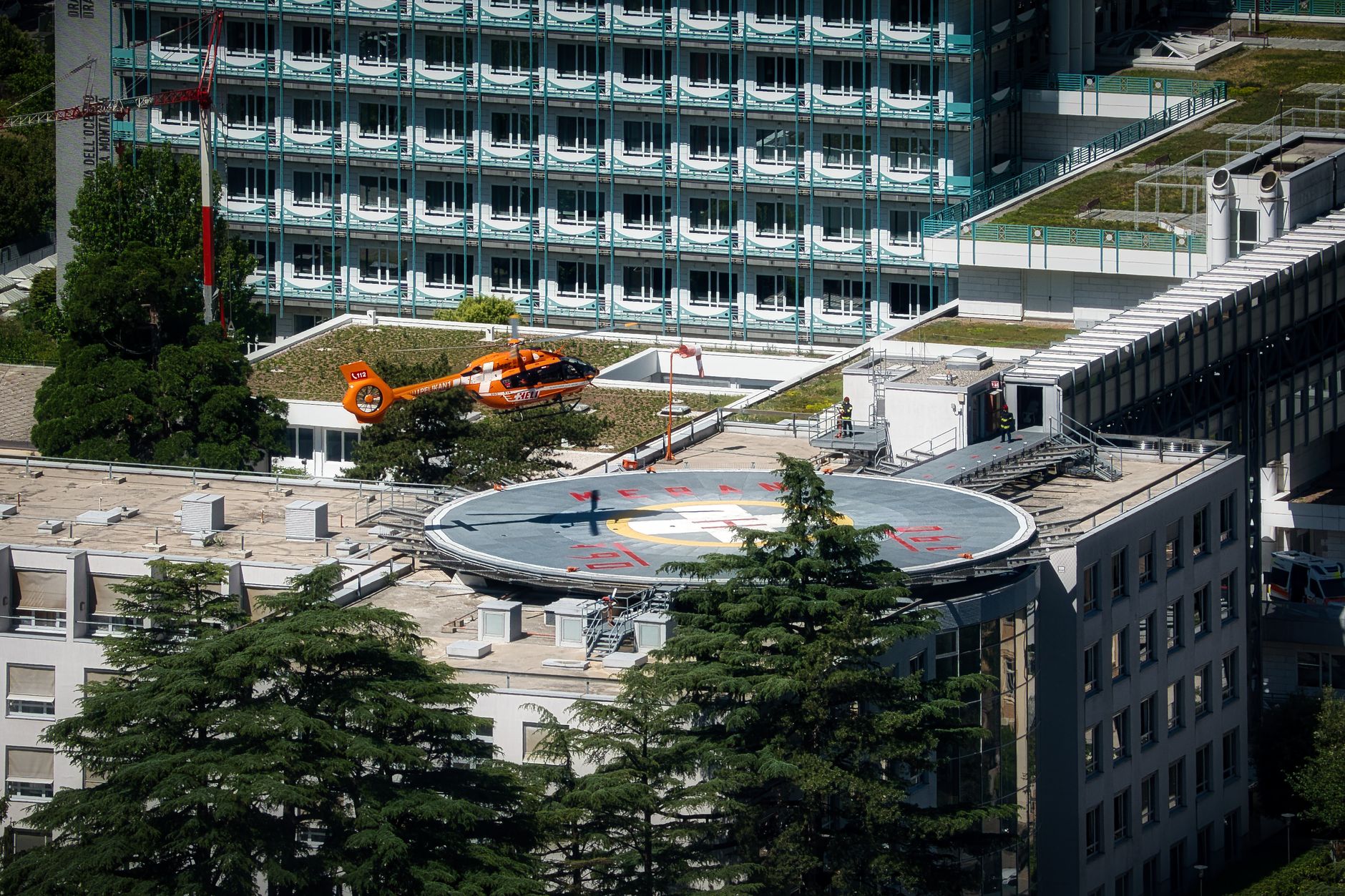 An elevated hospital helipad viewed from above, showing the marked landing area and surrounding rooftop.