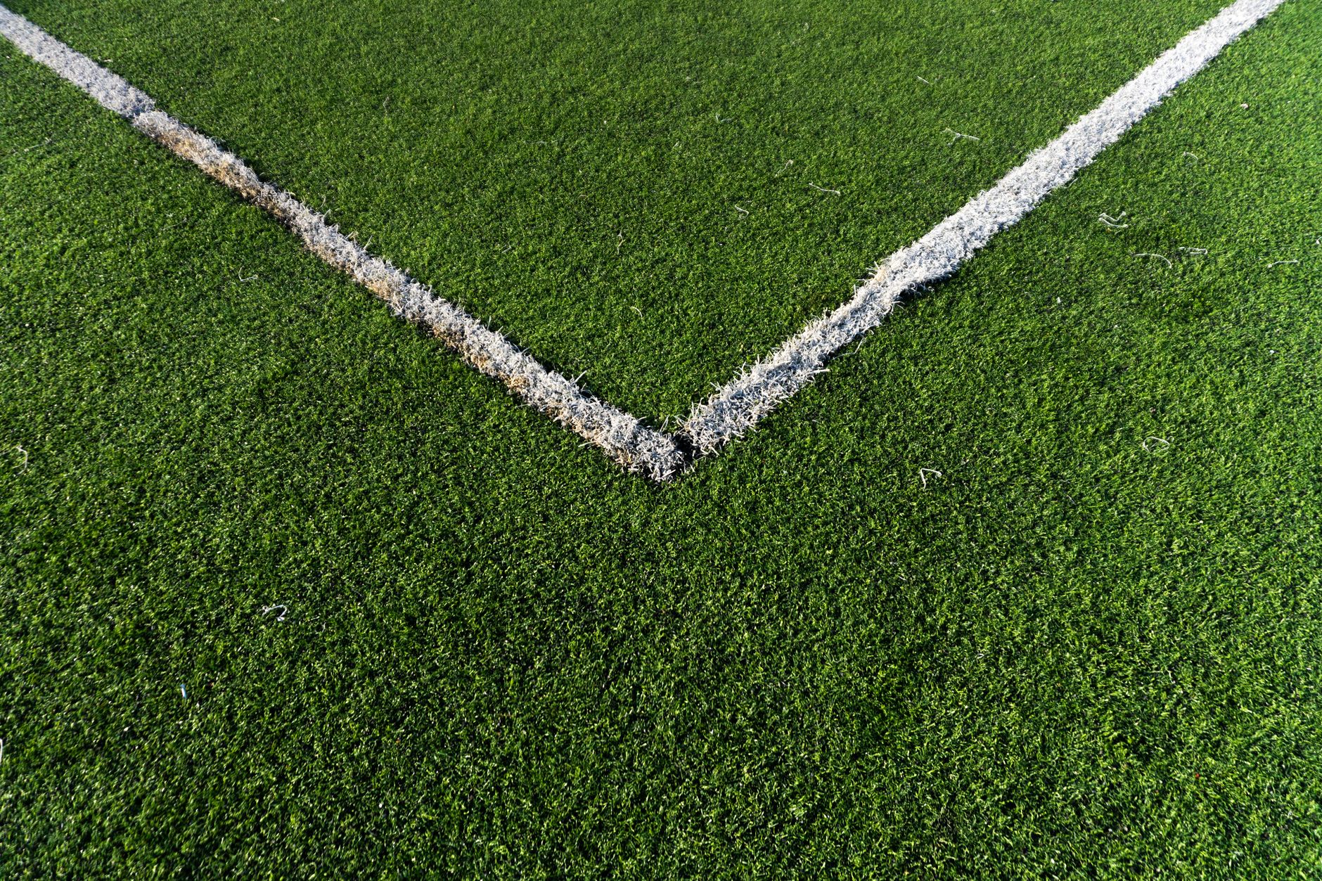 White game markings crossing synthetic turf, illustrating the lines and seams a cleaning route must cross gently.