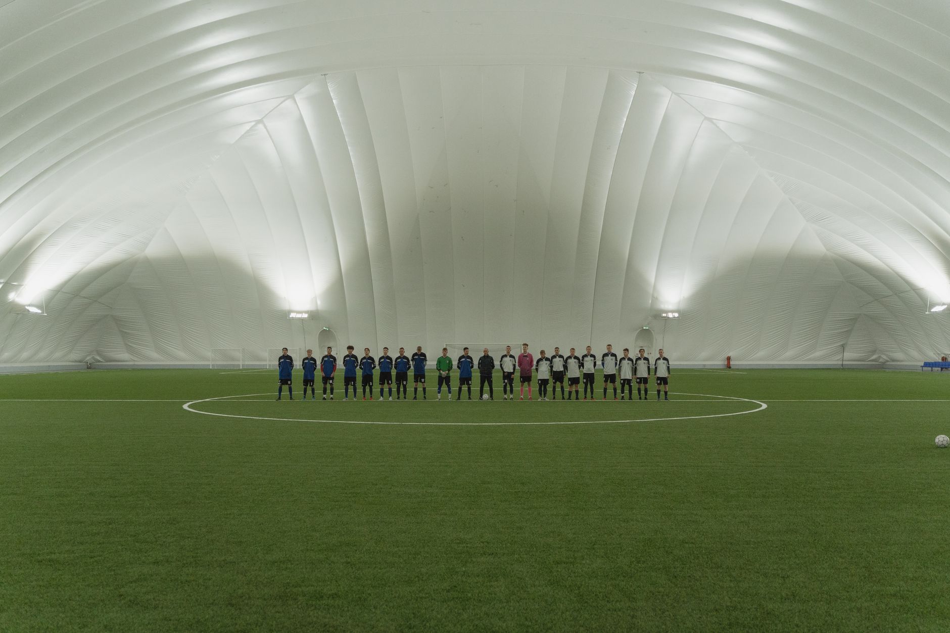 Wide view of an empty indoor soccer field with synthetic turf and side boards, the kind of surface this buyer's guide is about.