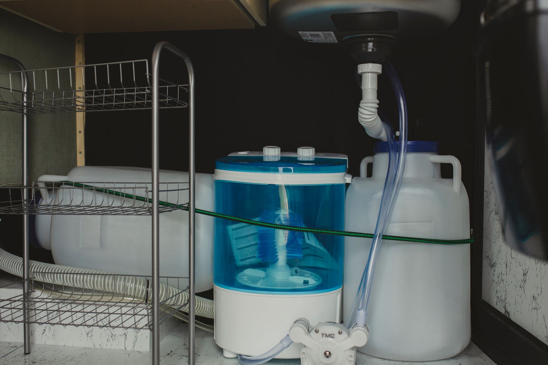 Compact plumbing beneath a commercial sink illustrates the restricted access around indoor grease traps.