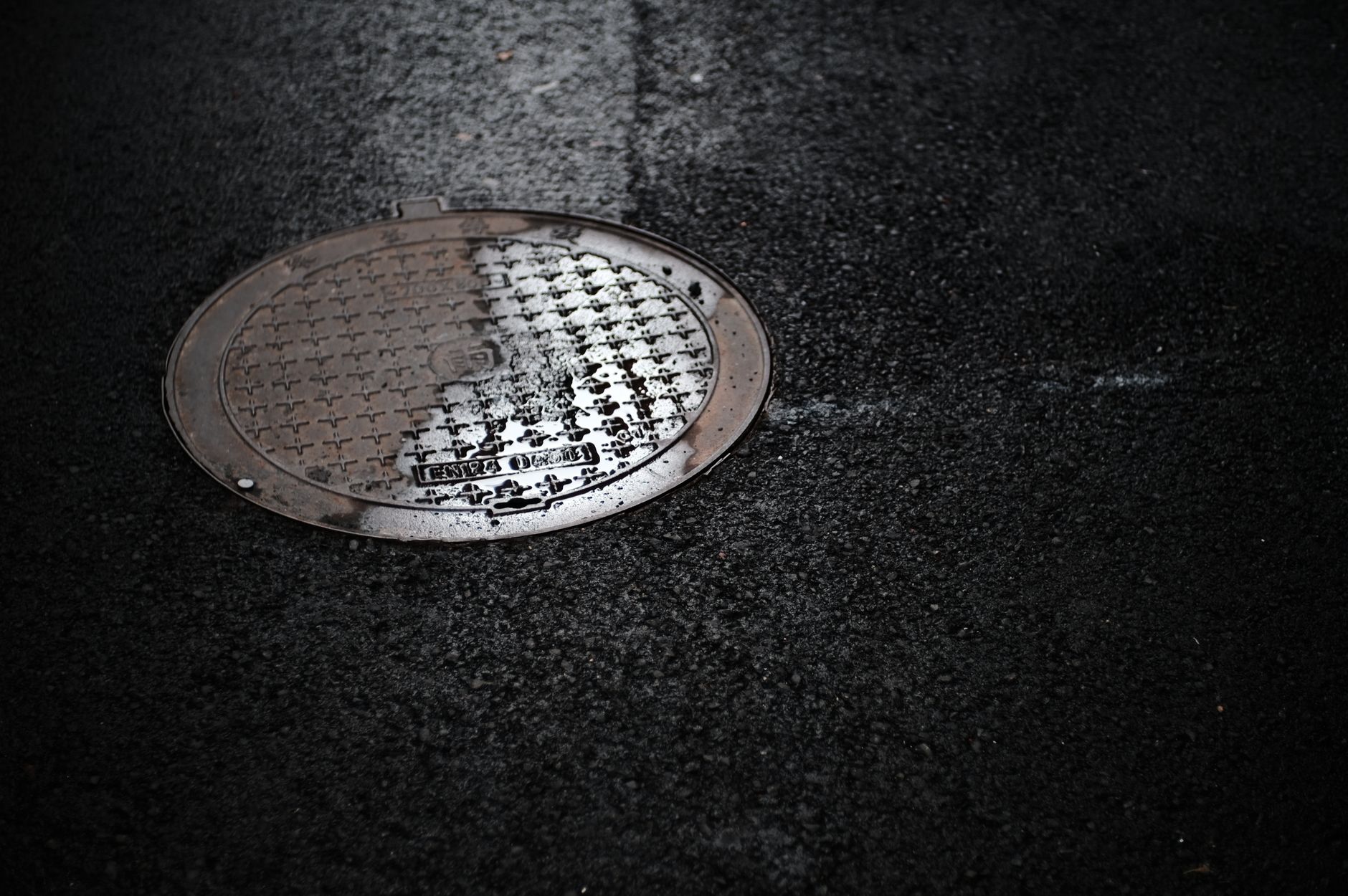 An open ground-level access cover shows the type of clearance crews must measure before an interceptor inspection.