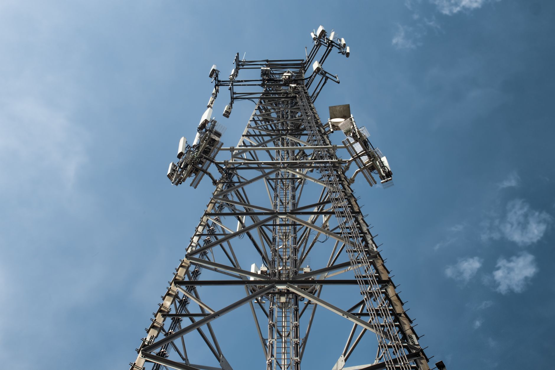 Outdoor cell site with tower and equipment area, illustrating remote telecom locations where weak backhaul and alert resilience matter.