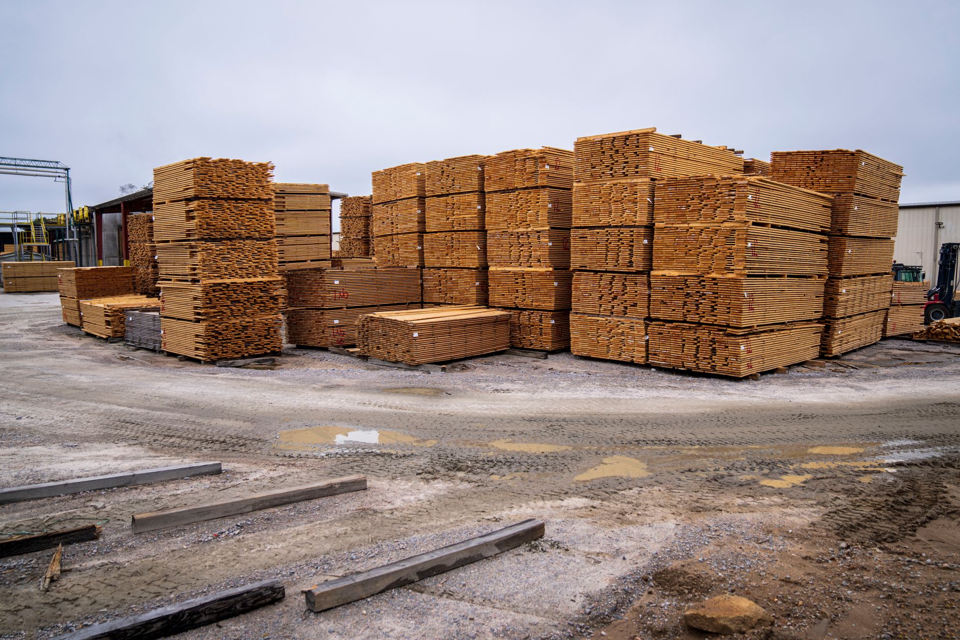Stacked lumber bundles in an outdoor yard where patrol routes must navigate changing aisles.