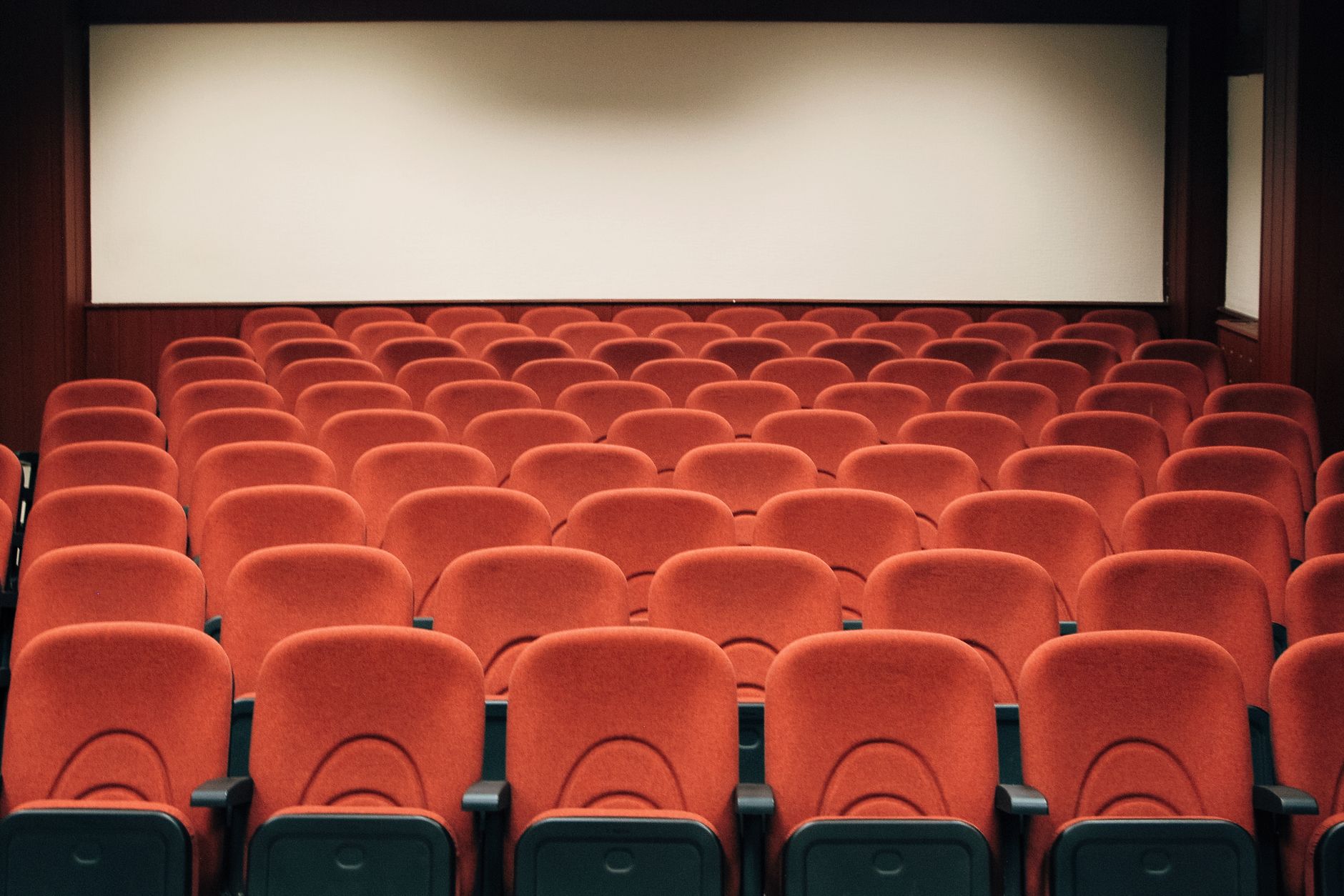 Rows of empty theatre seats after a late screening while the lobby reset is still underway.