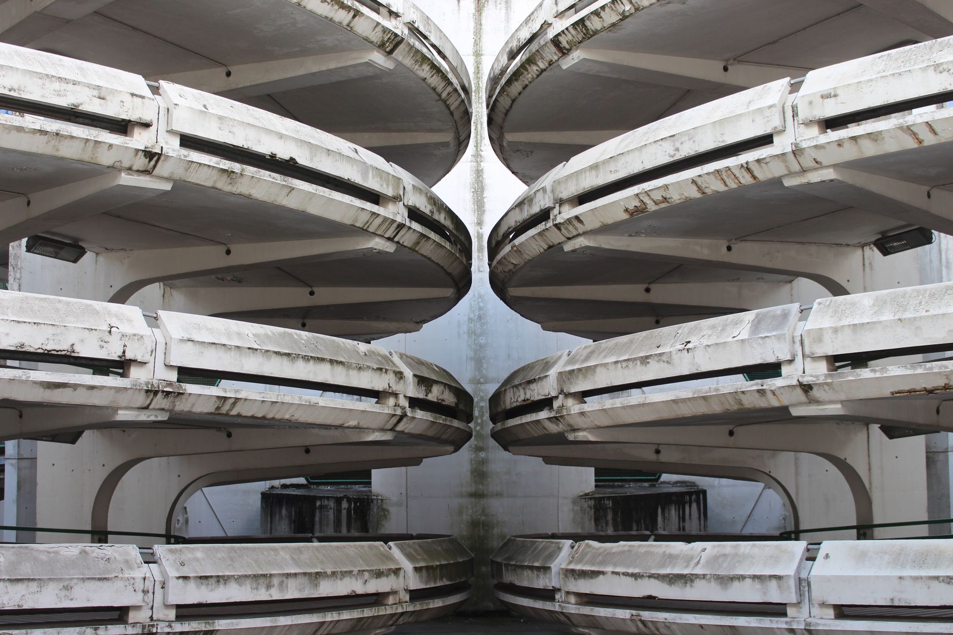 A close-up of a grimy concrete parking garage floor, covered in tire marks, dirt, and fluid stains, illustrating the challenge of manual cleaning.