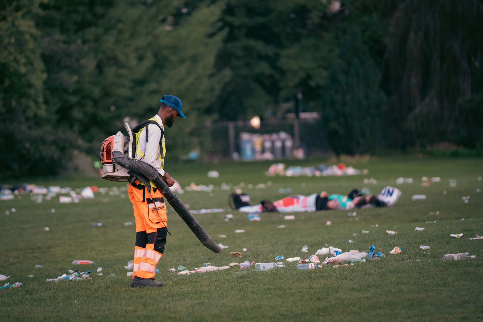 Debris and trash litter the floor of a large venue after an event, illustrating the scale of the manual cleaning challenge.