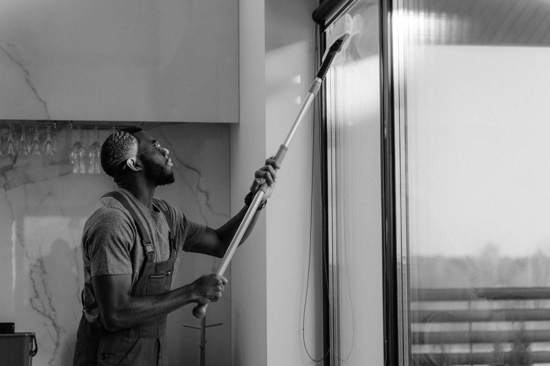 A day porter wipes lobby glass near an office entrance, showing the kind of detail work and human judgment a busy property needs.