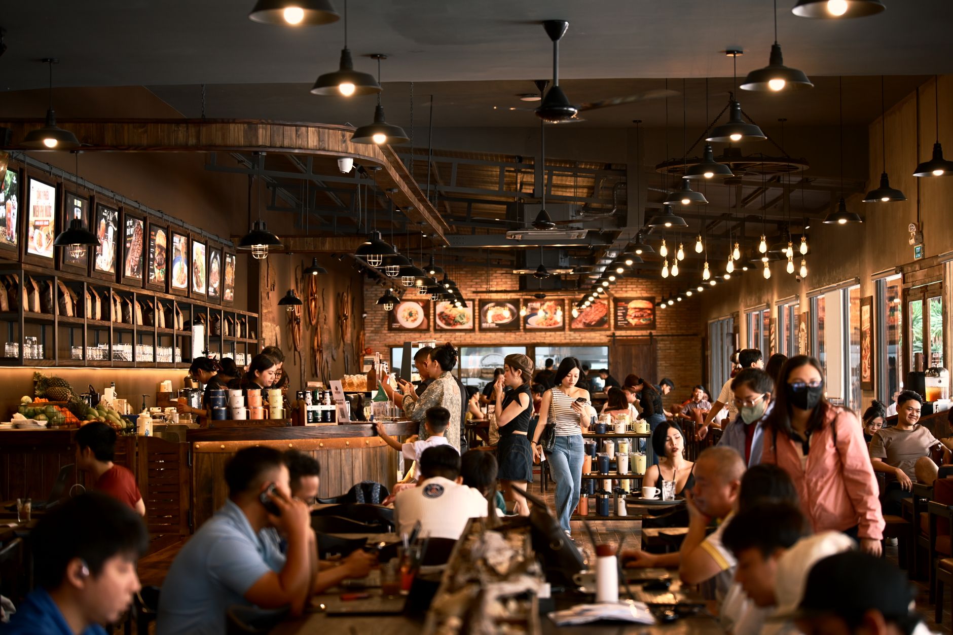 Restaurant staff and guests move through a crowded dining room during a busy service period.