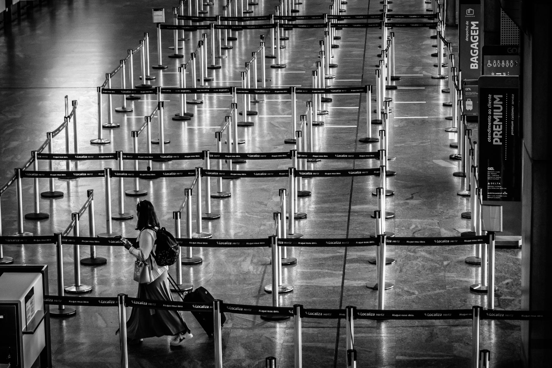 Movable stanchions form serpentine passenger lanes inside an airport terminal.