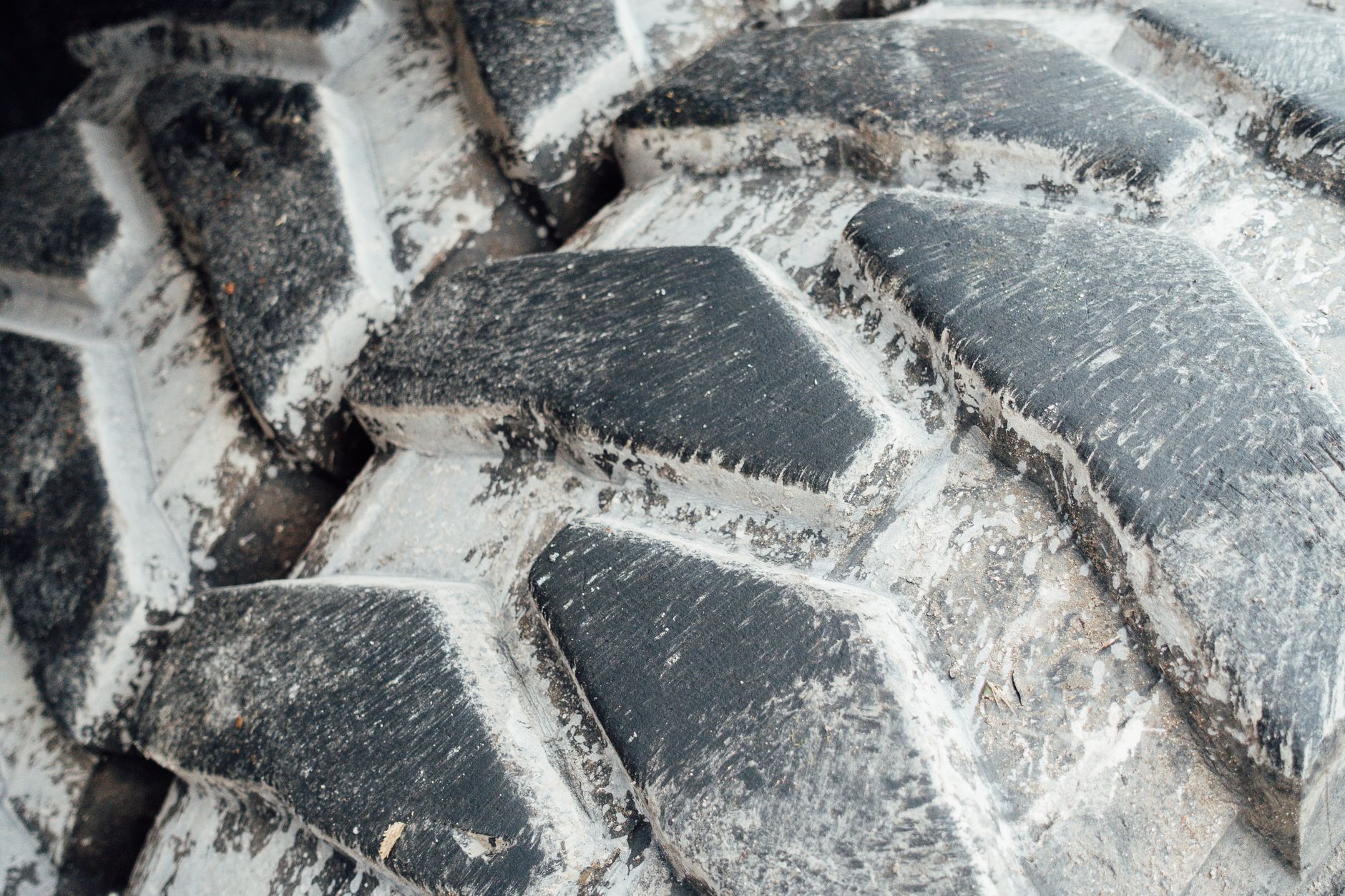 Close view of dried soil packed into the deep tread of a farm tractor tire.