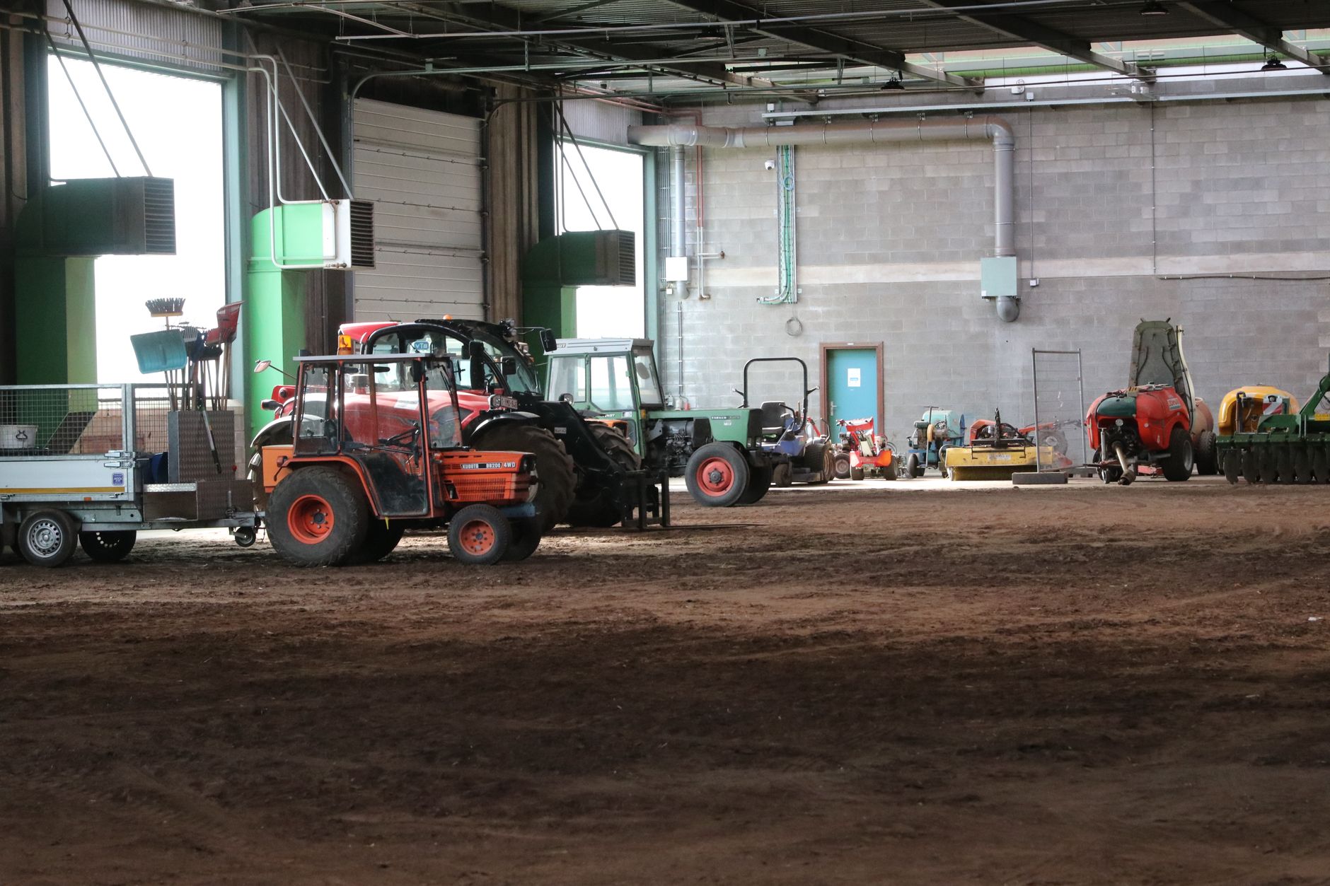 Farm equipment positioned inside a spacious service workshop with marked travel areas.