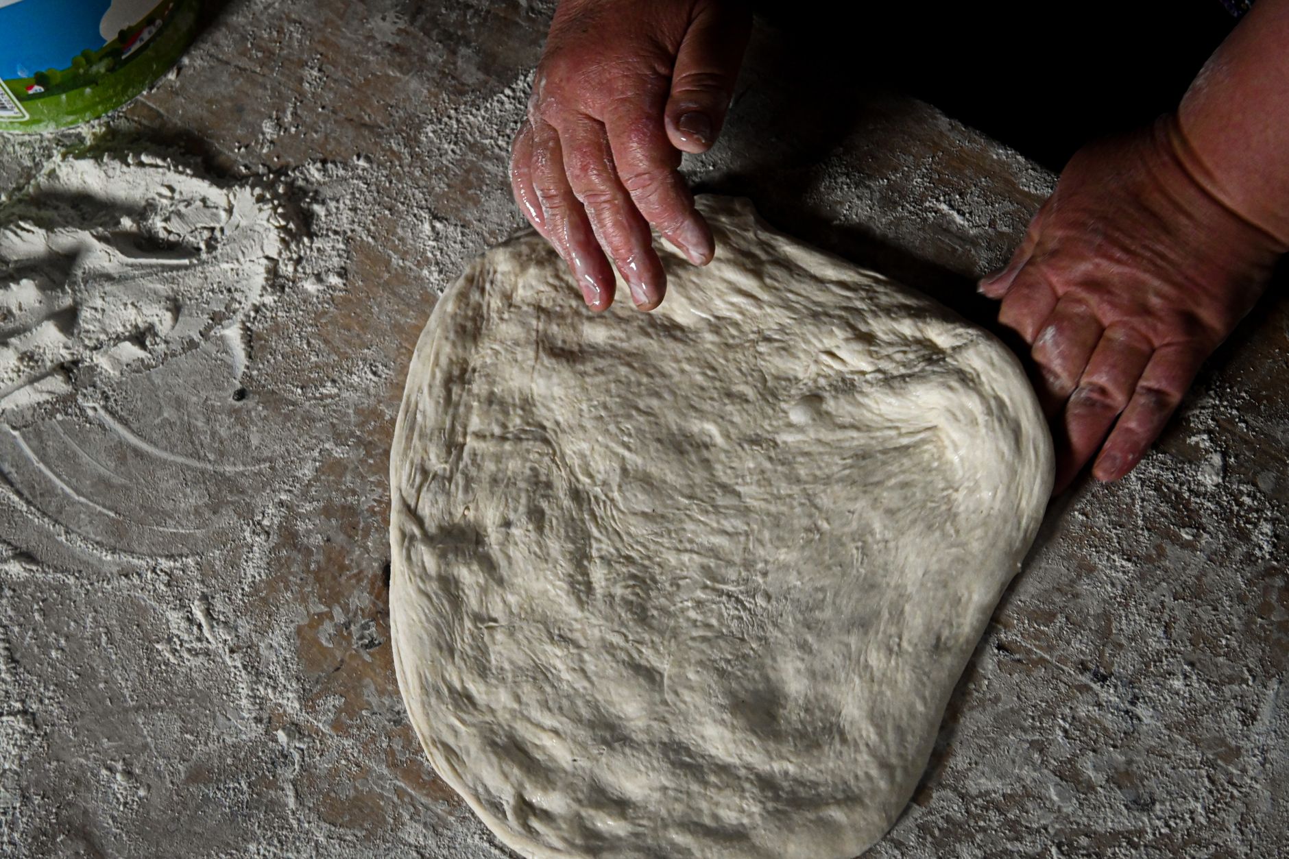 Flour dust on a prep table illustrating dry debris that must be swept before wet scrubbing.