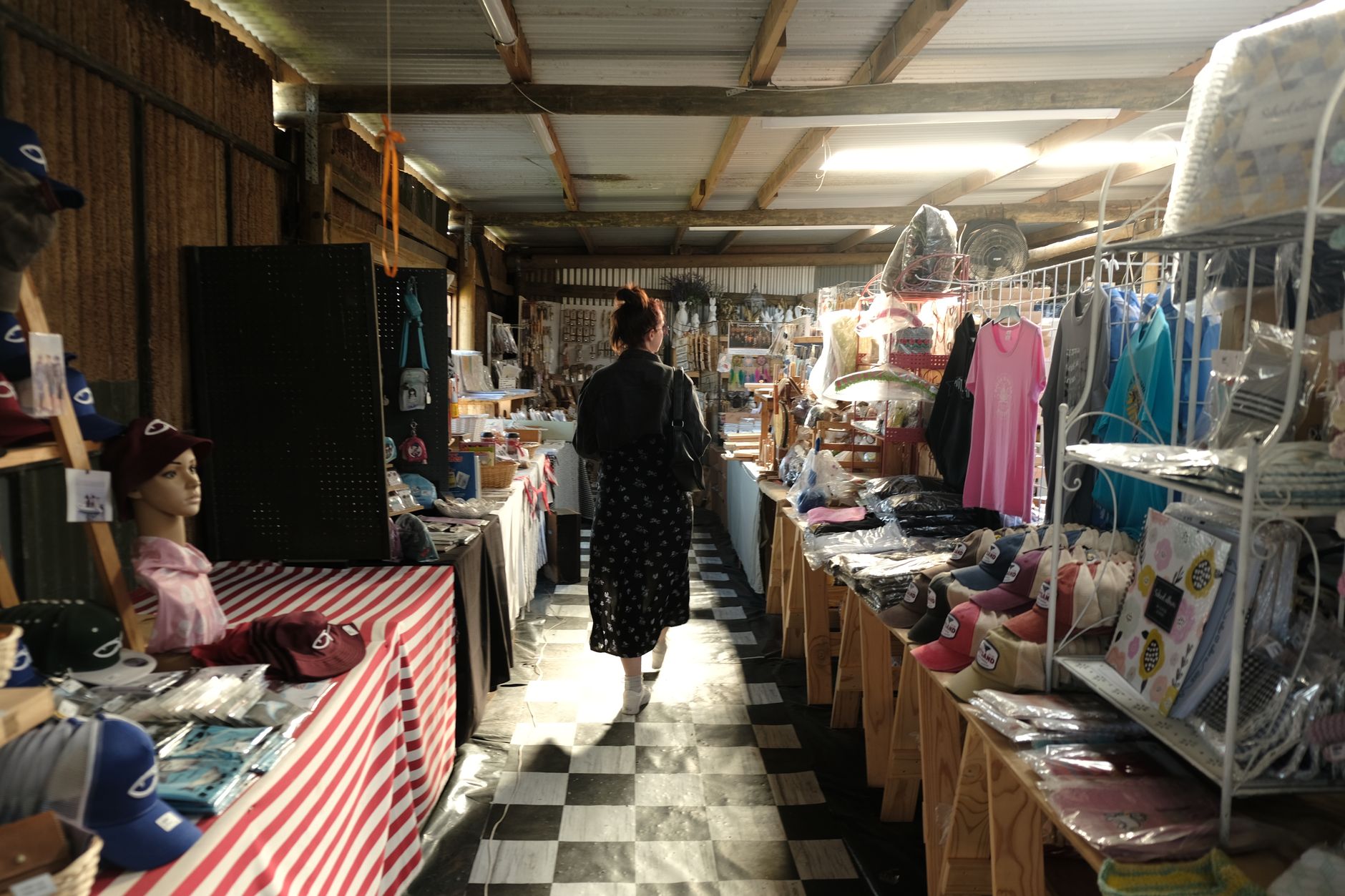 Rows of indoor market stalls with narrow aisles where after-close floor scrubbing must respect cords, rugs, and table legs.
