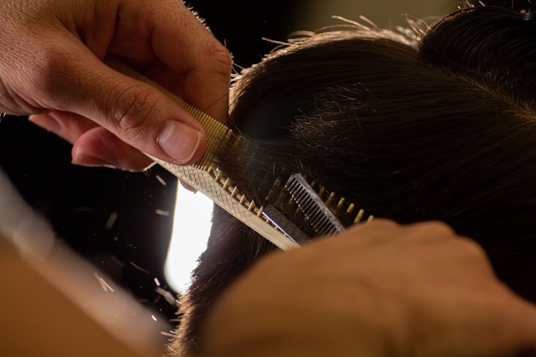 Cosmetology students work at closely arranged stations in a busy beauty-school classroom.