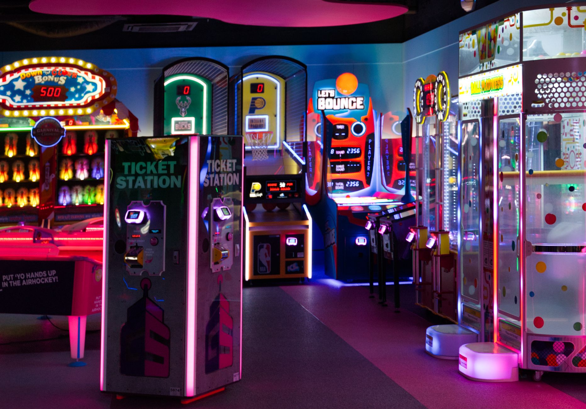 Carpeted aisles wind between arcade games in a mixed-surface entertainment venue.