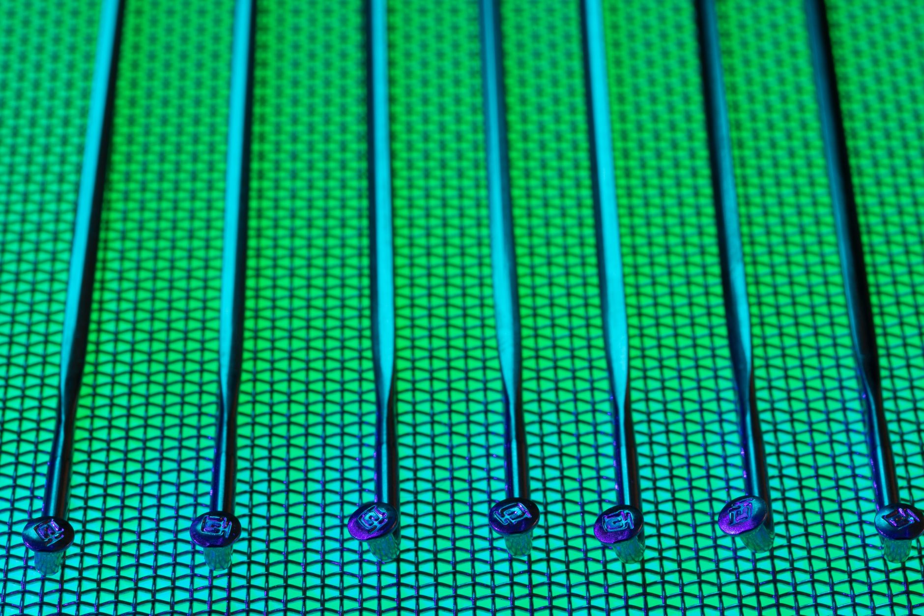 A technician in a full cleanroom suit holds a silicon wafer with tweezers inside a highly controlled semiconductor fab.
