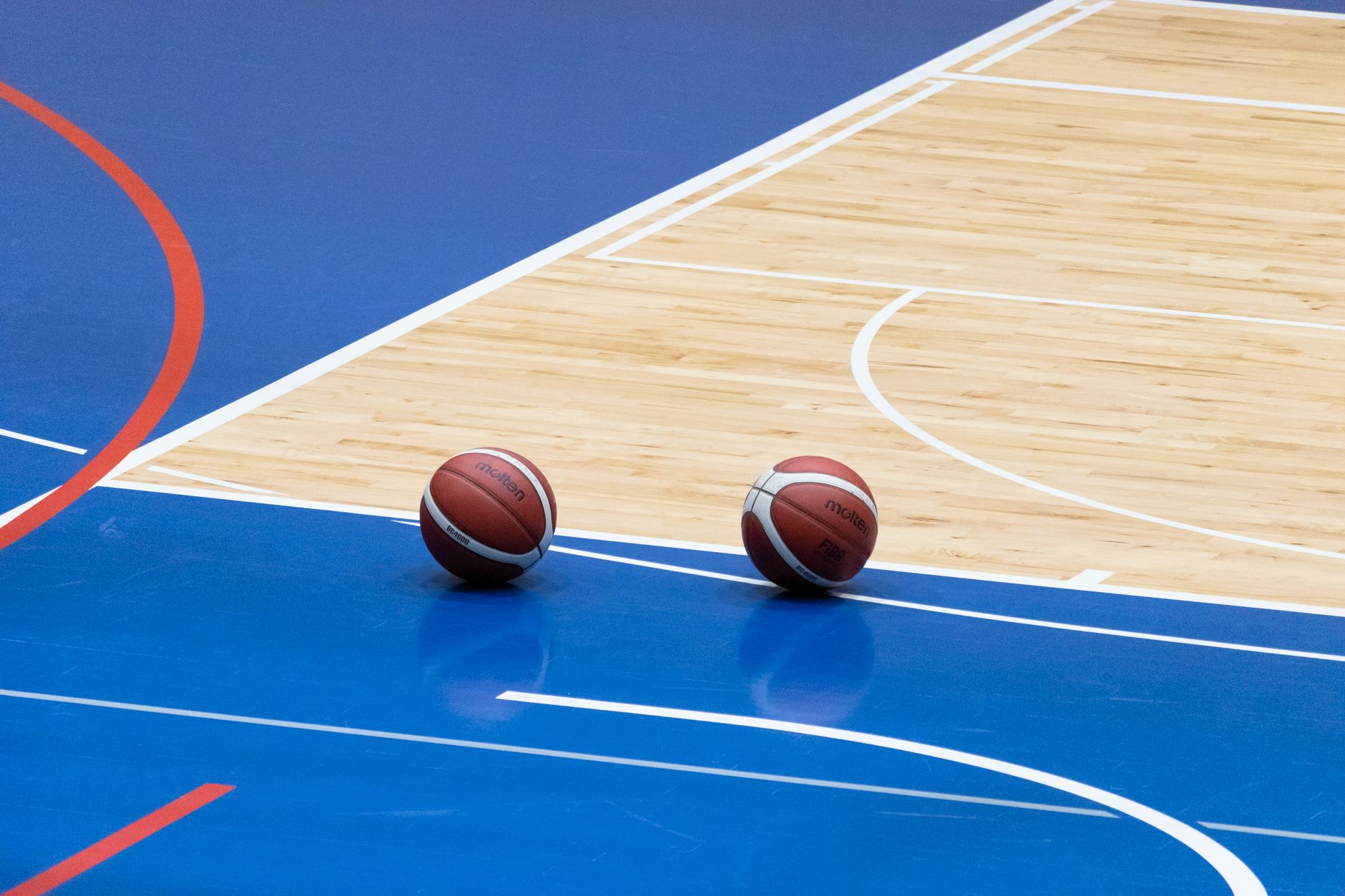 A close-up shot of a polished hardwood basketball court, its gleaming surface reflecting the overhead lights, emphasizing floor safety.