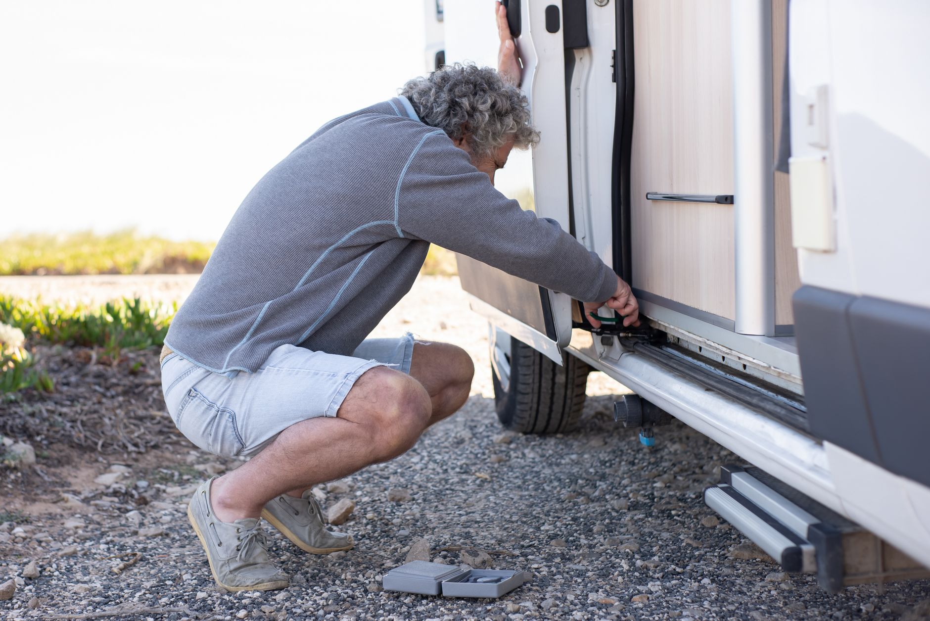 A technician works across the long roof surface of a recreational vehicle.