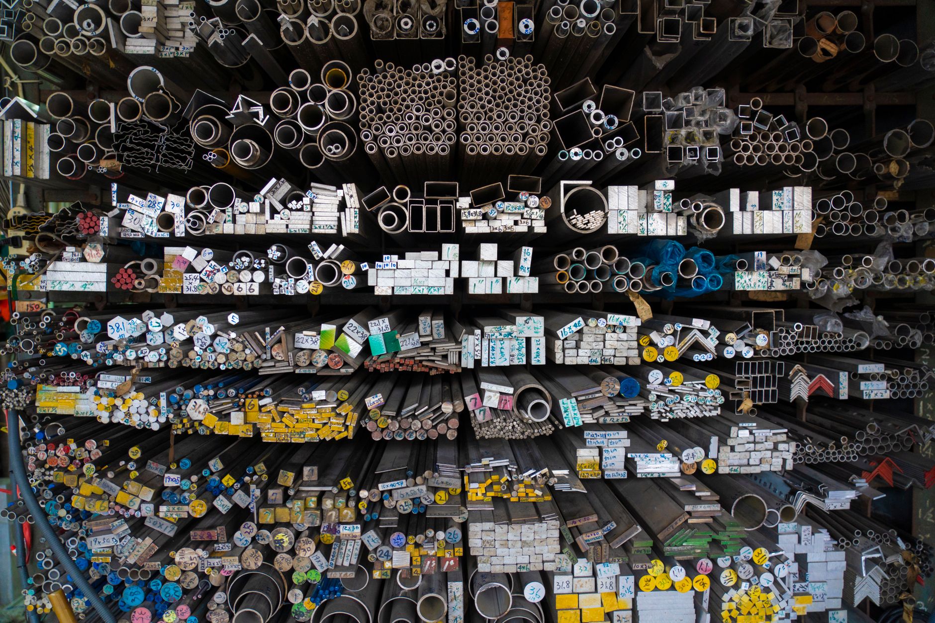 Long metal bars stored together illustrate the uniform stock required for spindle-fed turning.