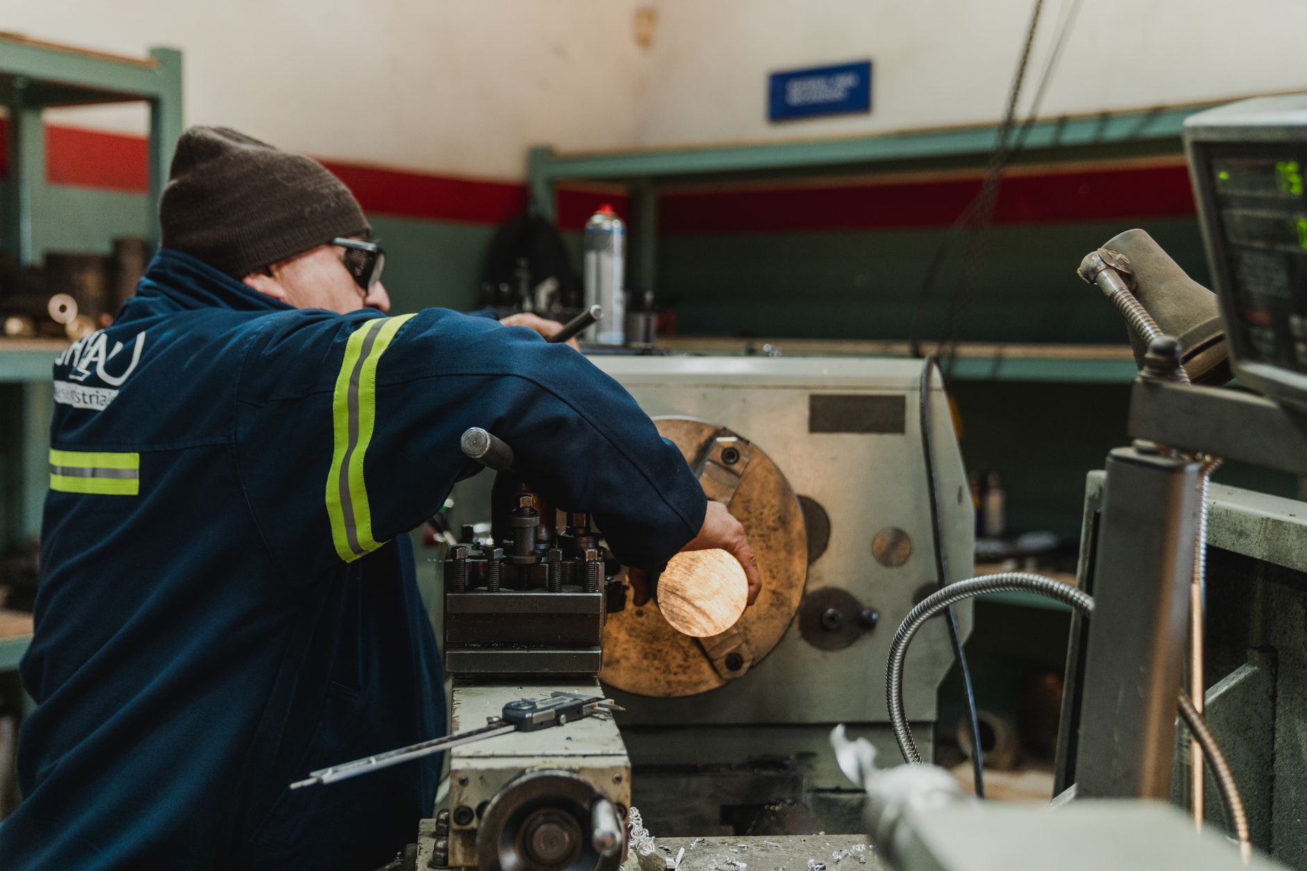 A machinist works among metal parts and production equipment in a busy machine shop.