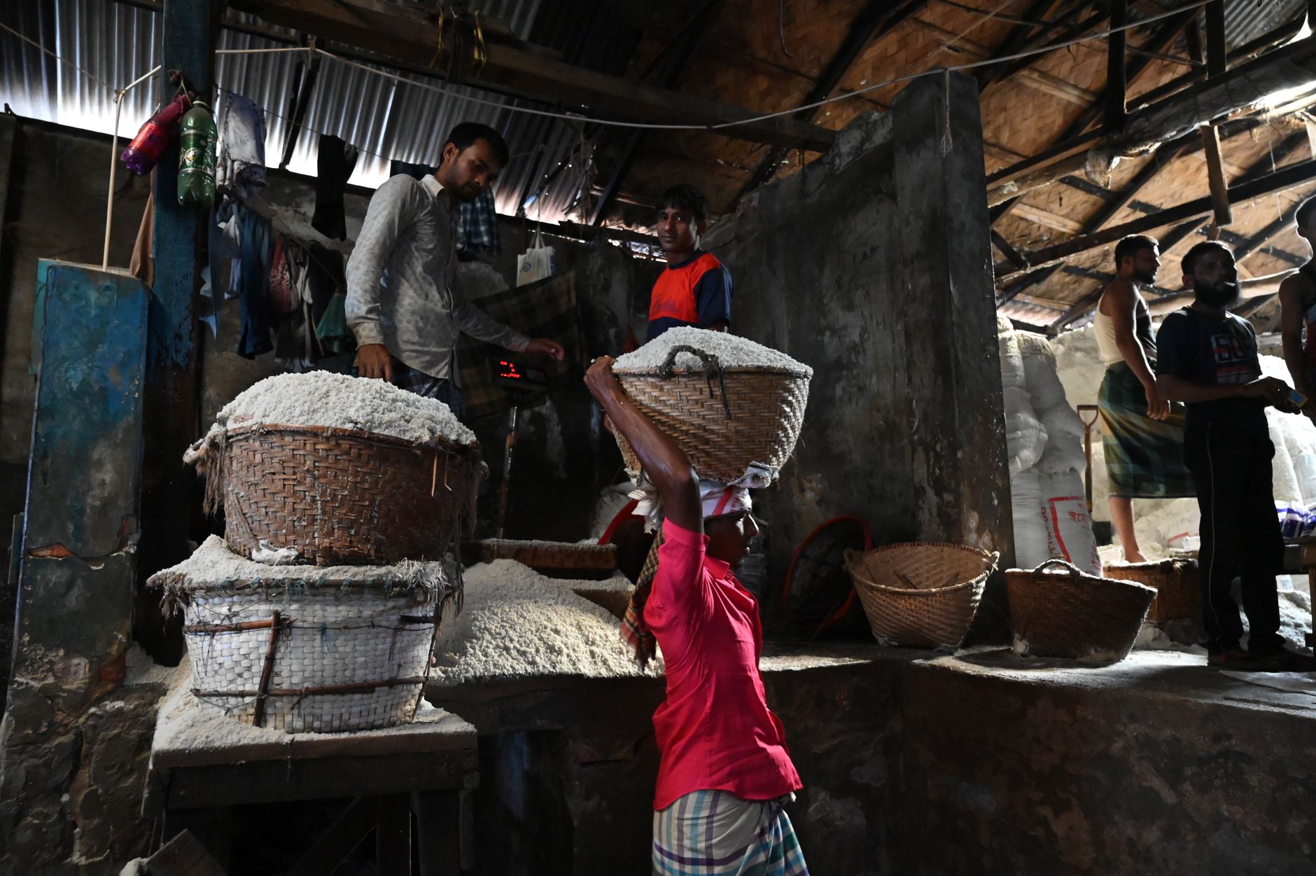 Workers handling filled grain sacks as they move through a bagging and storage area.