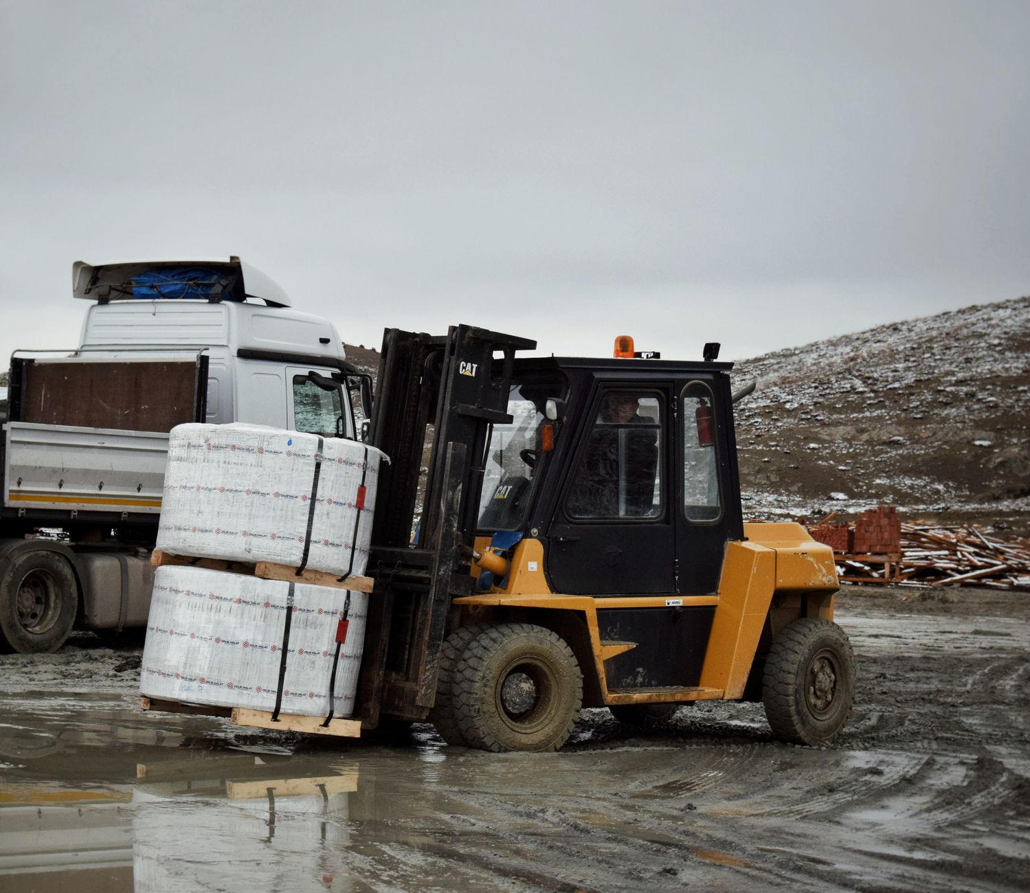A forklift transporting pallets of bagged agricultural products through a warehouse.