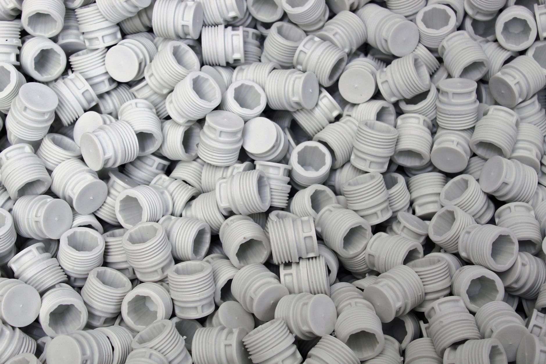 Bins of freshly molded plastic parts cooling beside an industrial press area.