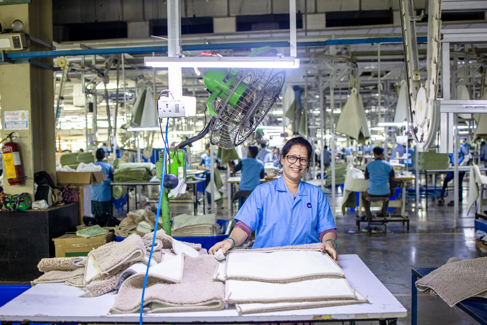A factory worker collaborates with machinery on a modern, well-lit production line, representing the choice between collaborative and isolated automation.