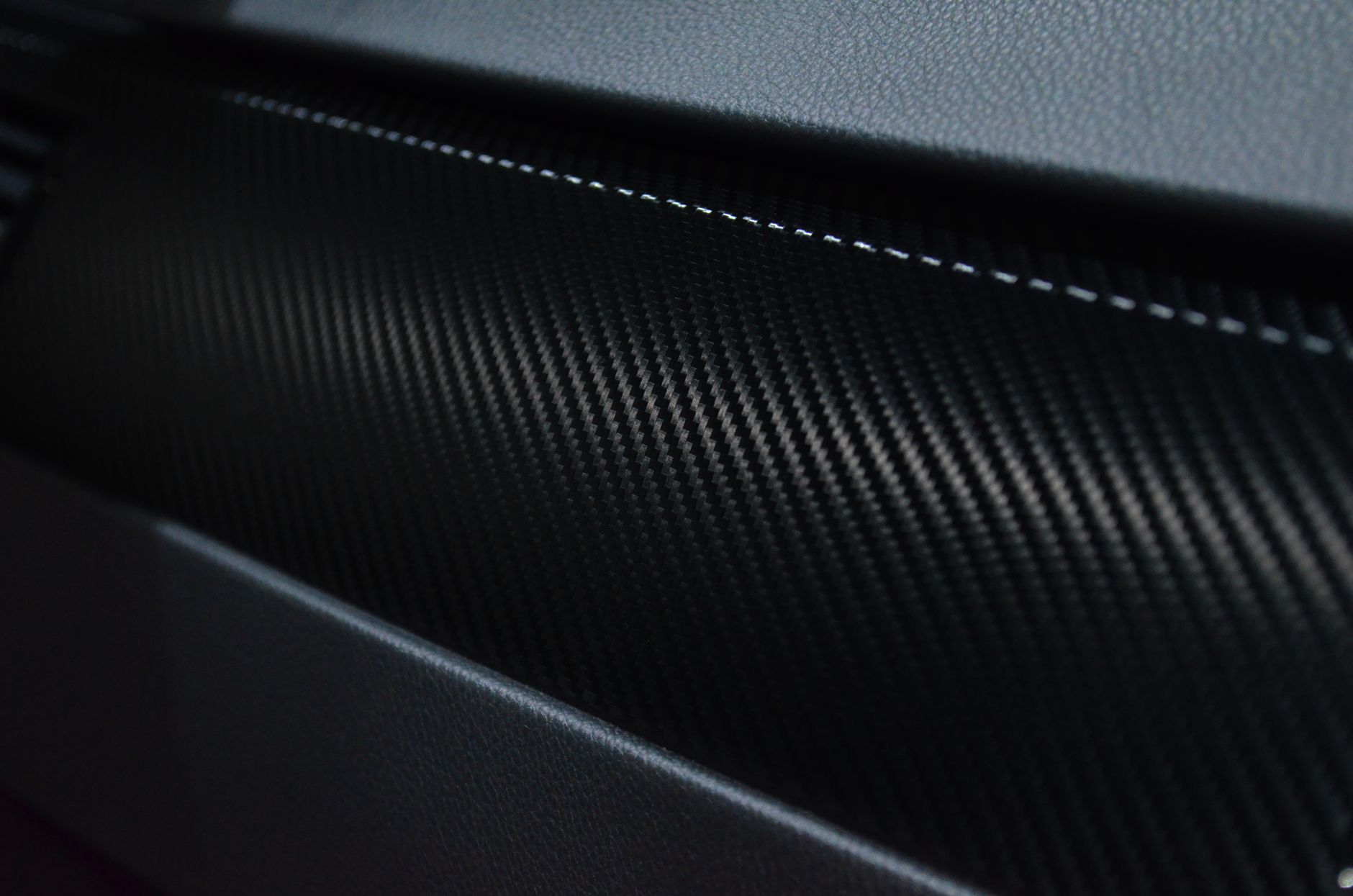 A close view of flexible carbon-fiber material being positioned by gloved hands.