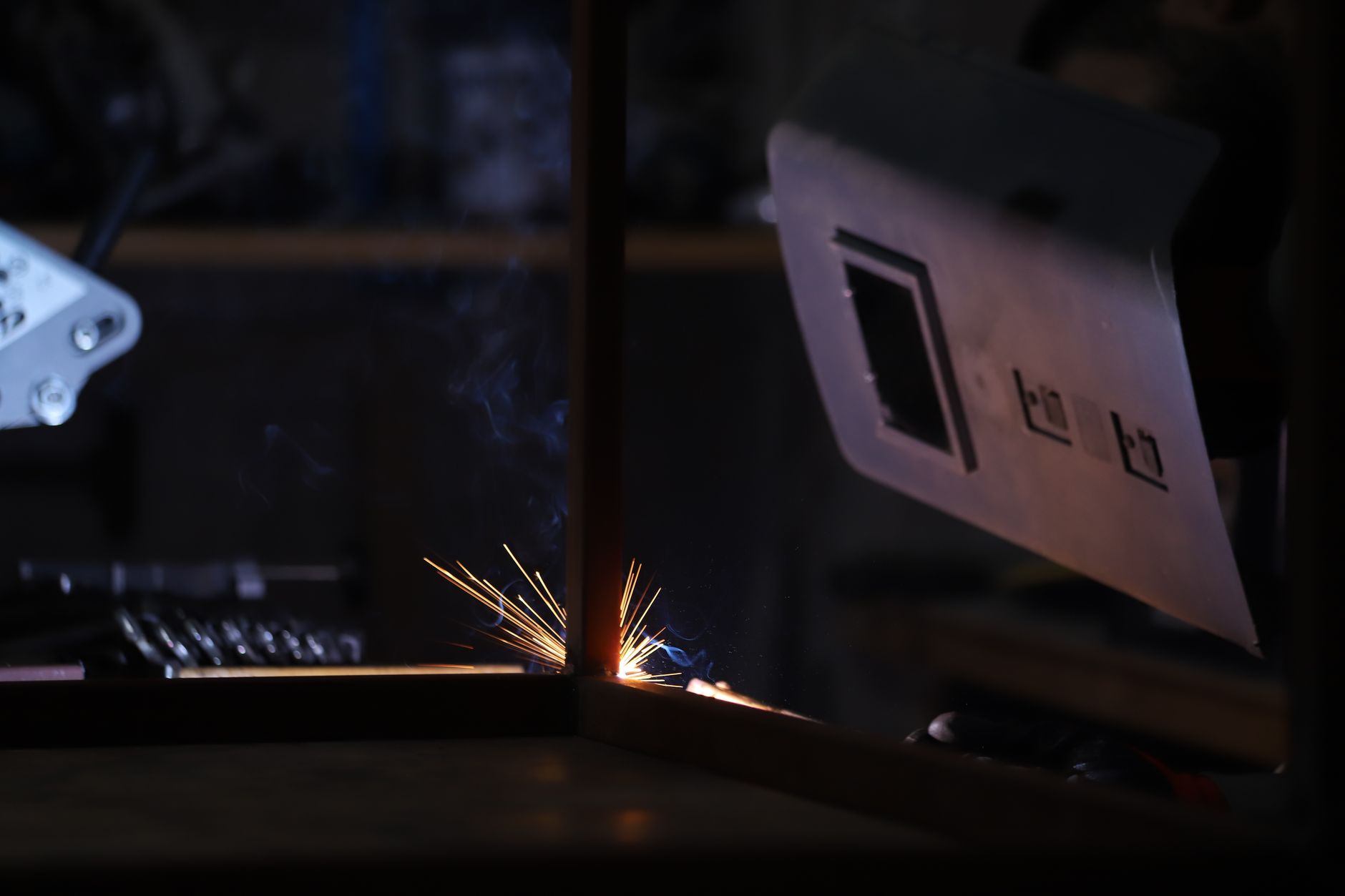 Welding sparks in a fabrication shop, the environment where torch nozzles collect spatter between cycles.