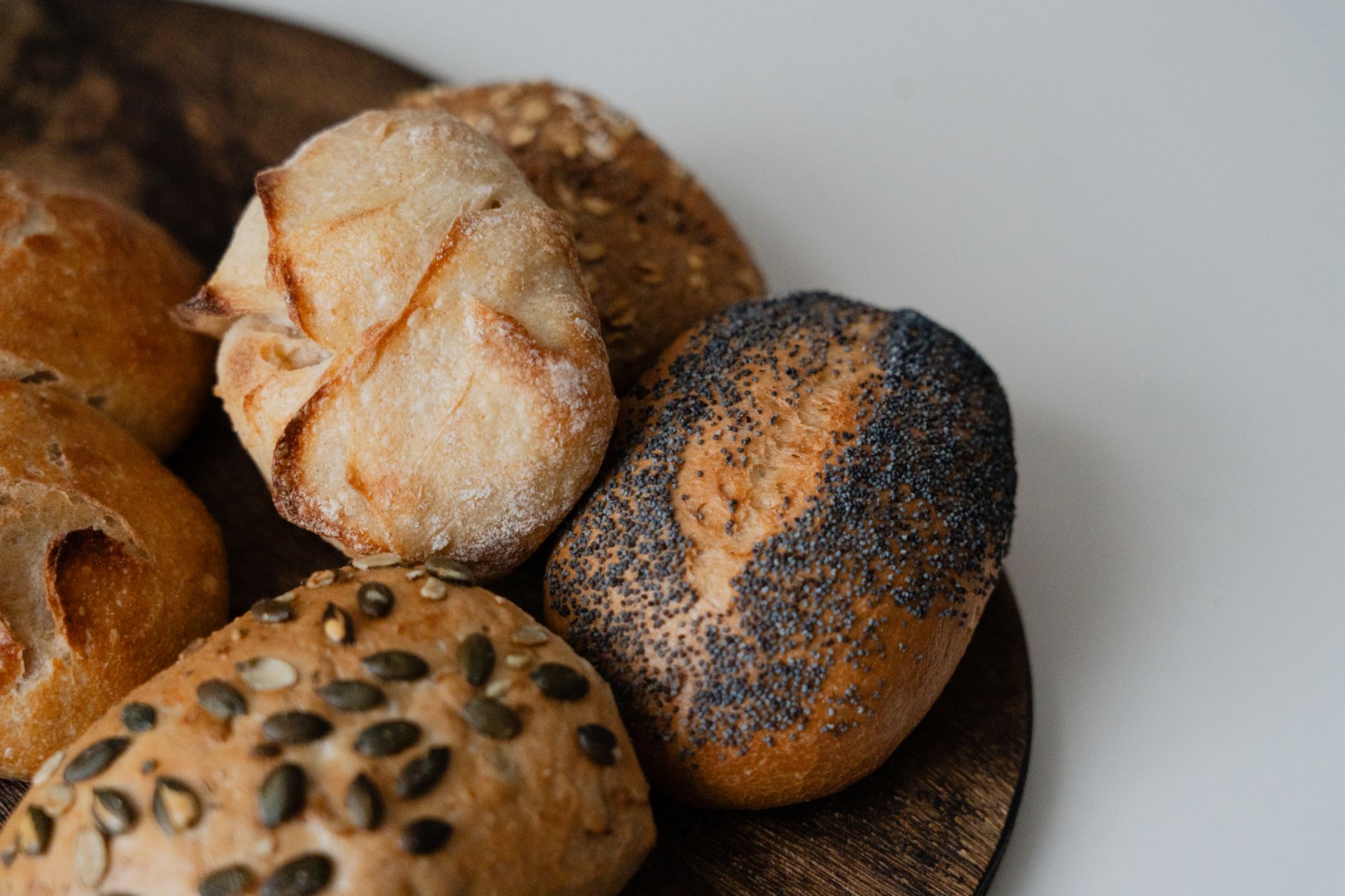 Freshly baked rolls with delicate crusts and varied surfaces rest together on a tray.