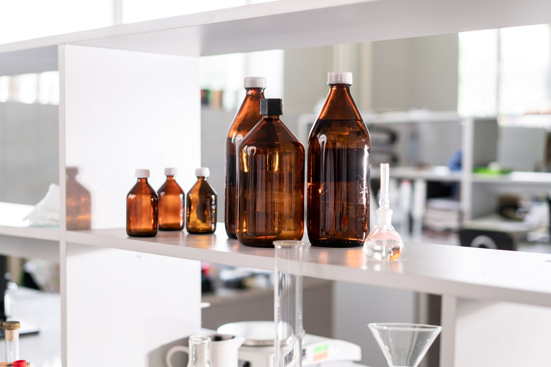 Assorted capped bottles on a lab shelf showing the container mix a capping cell must handle.