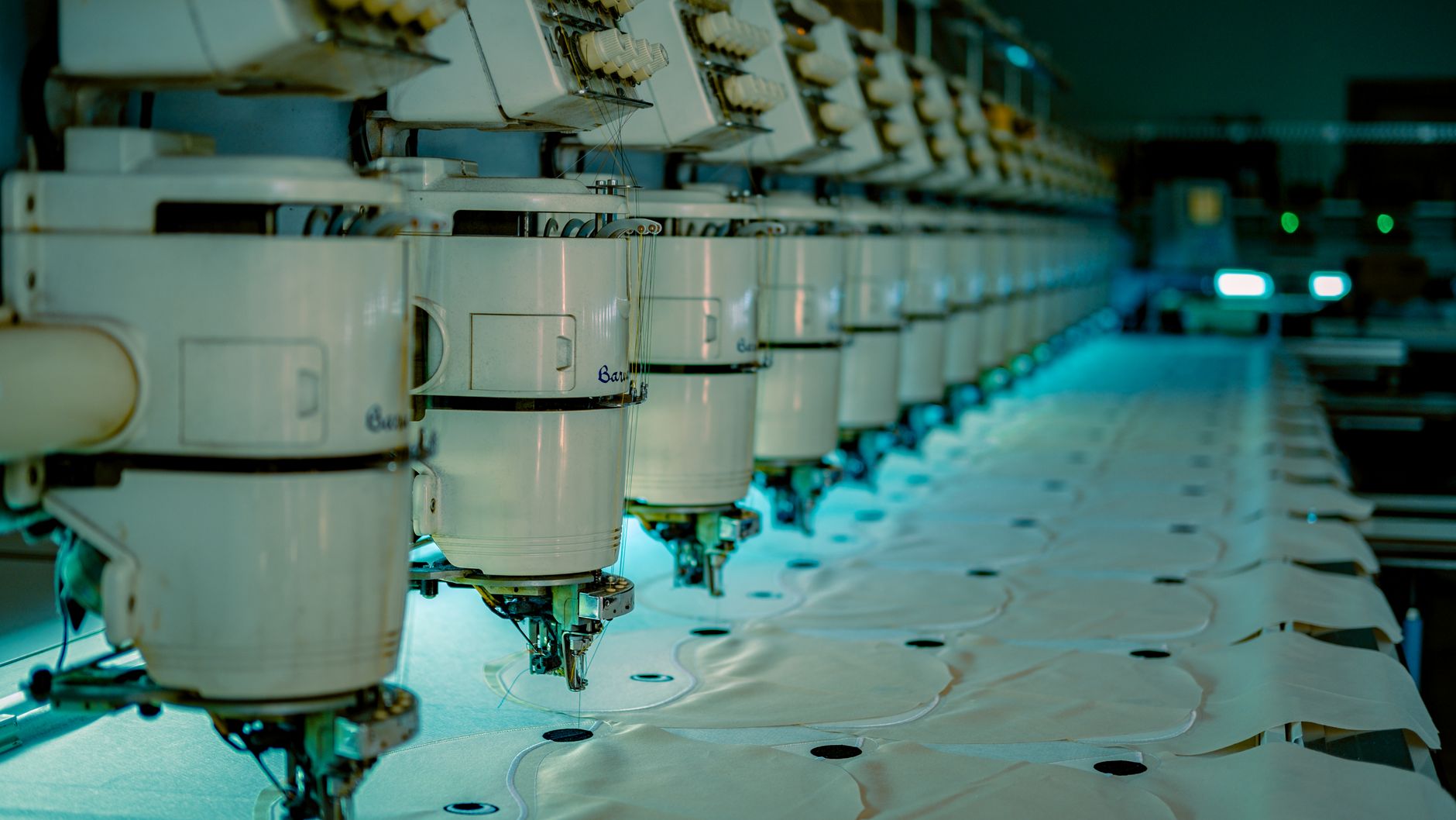Contract embroidery production floor where hooped blanks queue before multi-head machines.