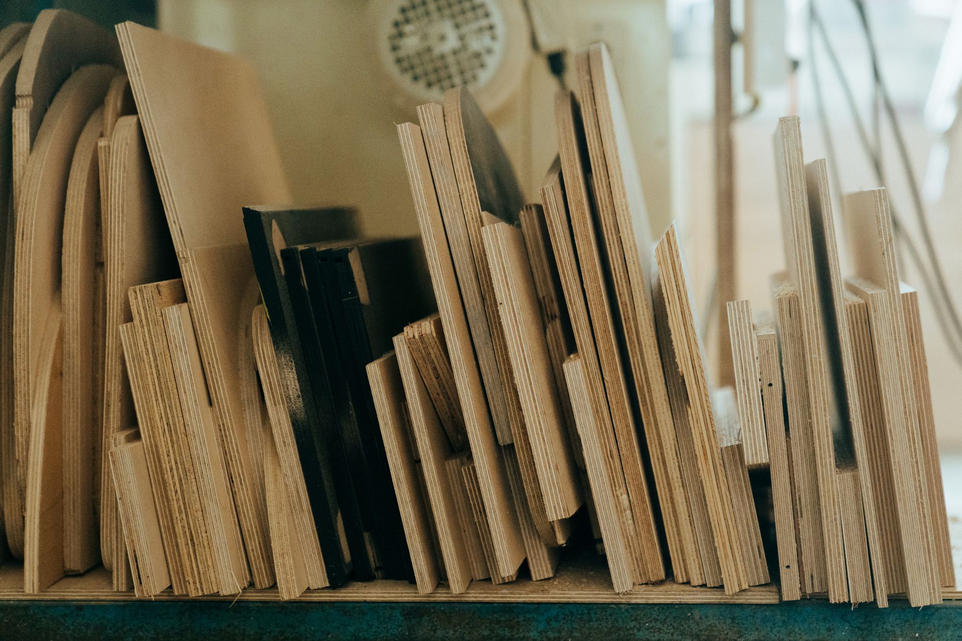 Stacks of sheet goods and cut panels staged in a cabinet shop, illustrating repeat part families that are practical first targets for machine tending.