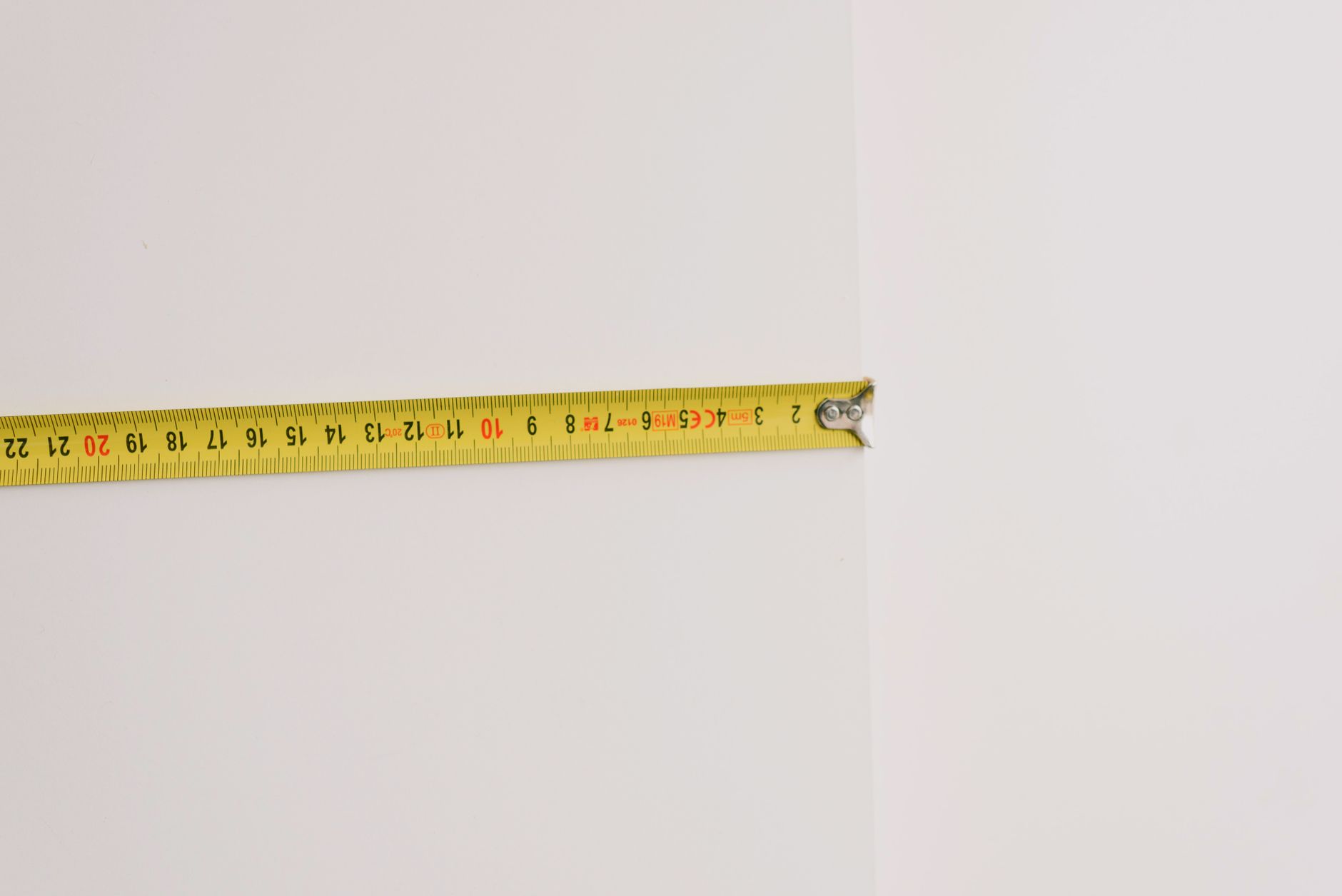 A measuring tape extended along a wall, evoking length checks before custom blinds ship.