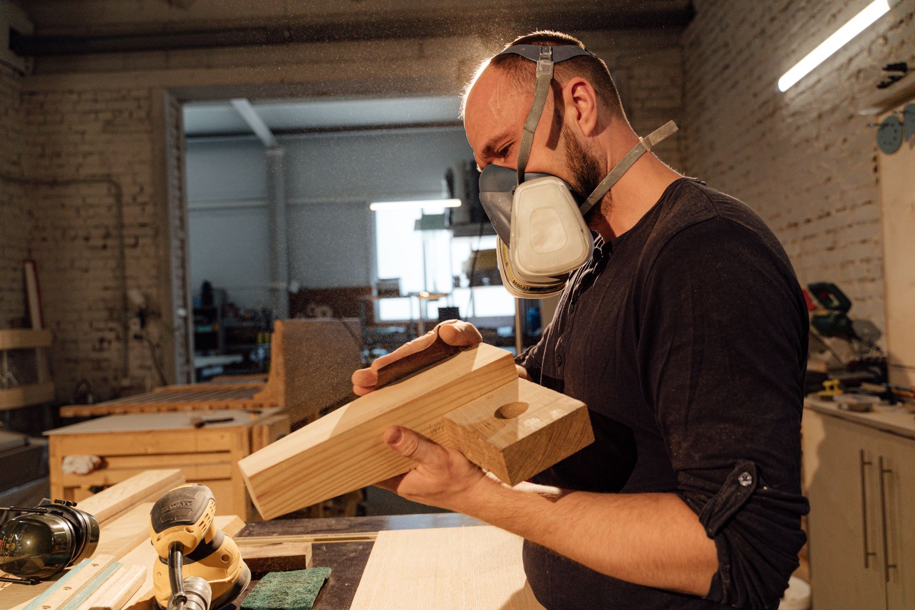 A workshop dust-extraction system captures airborne debris near a finishing station.