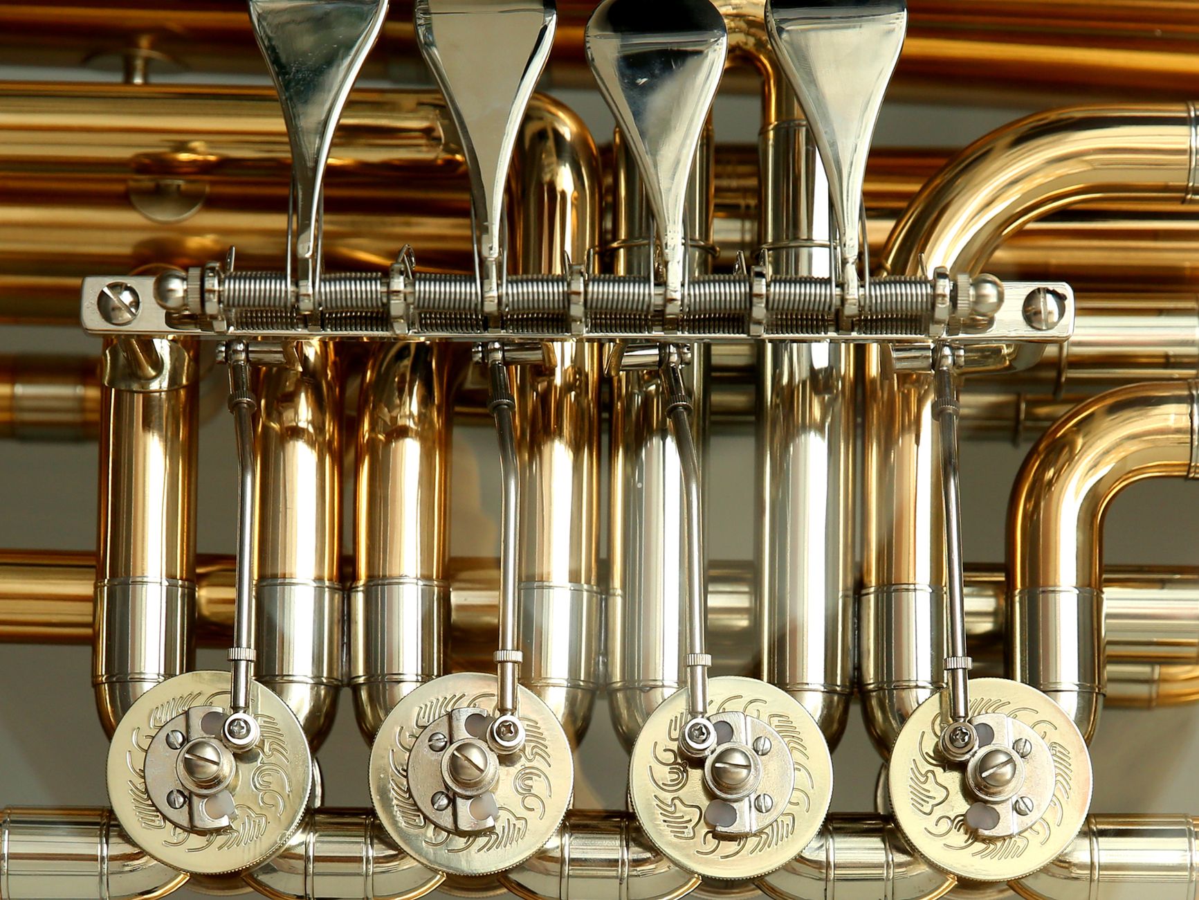 A craftsperson hand-polishes the reflective brass surface of a musical instrument in a workshop.