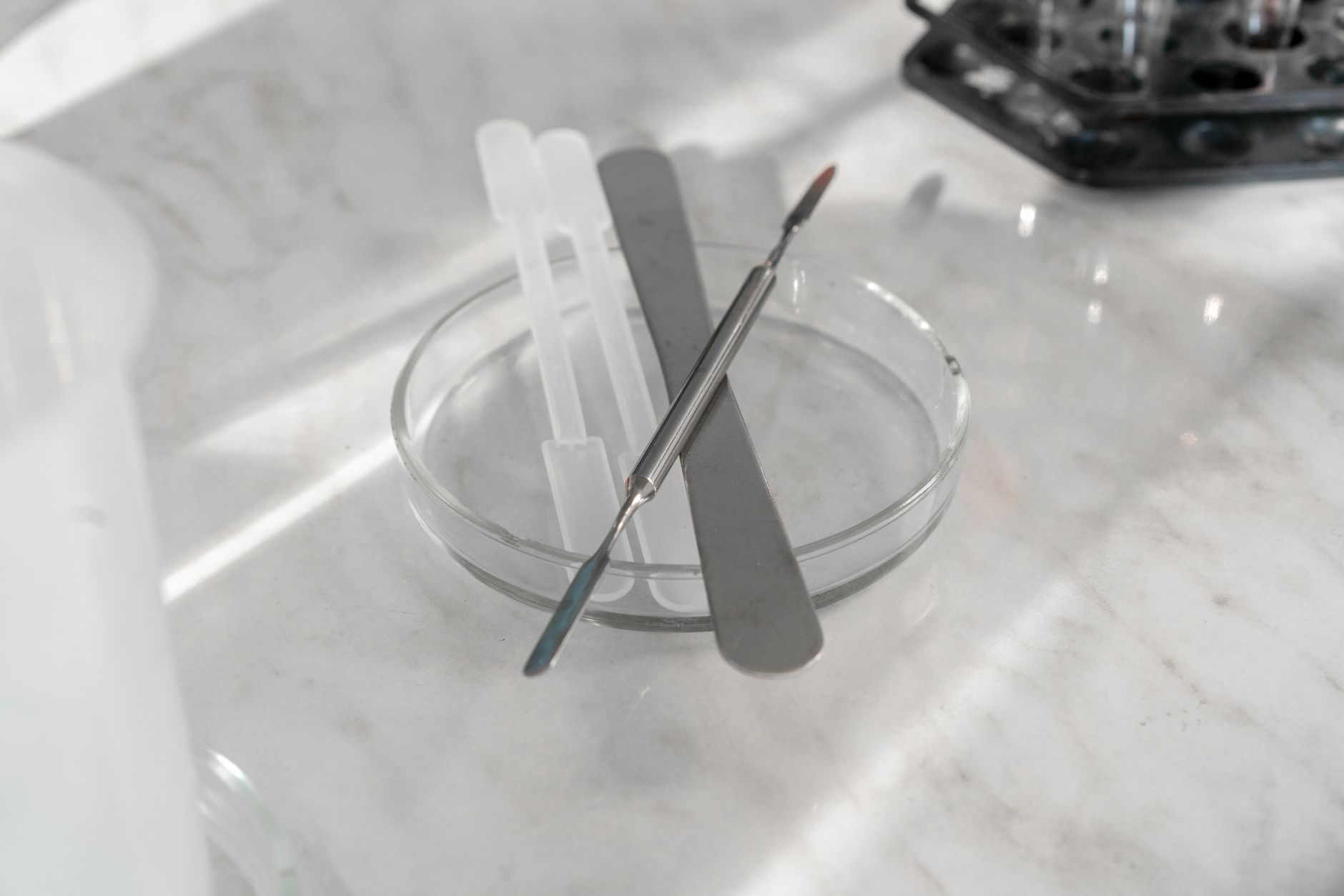 A gloved technician wipes a stainless work surface in a presterilization kit assembly area to control particles and residue.