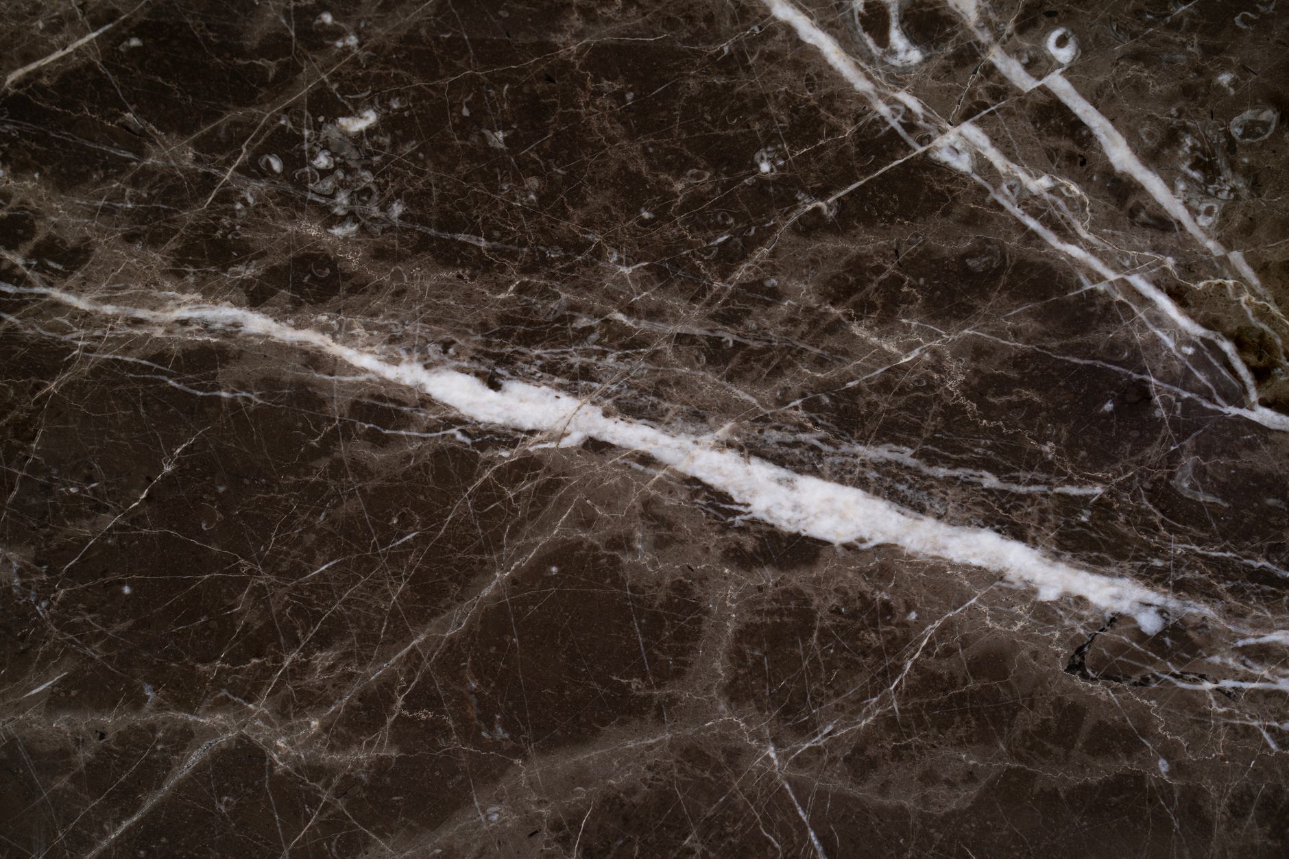 A fabricator polishing the edge of a stone countertop piece at a bench in a countertop shop.