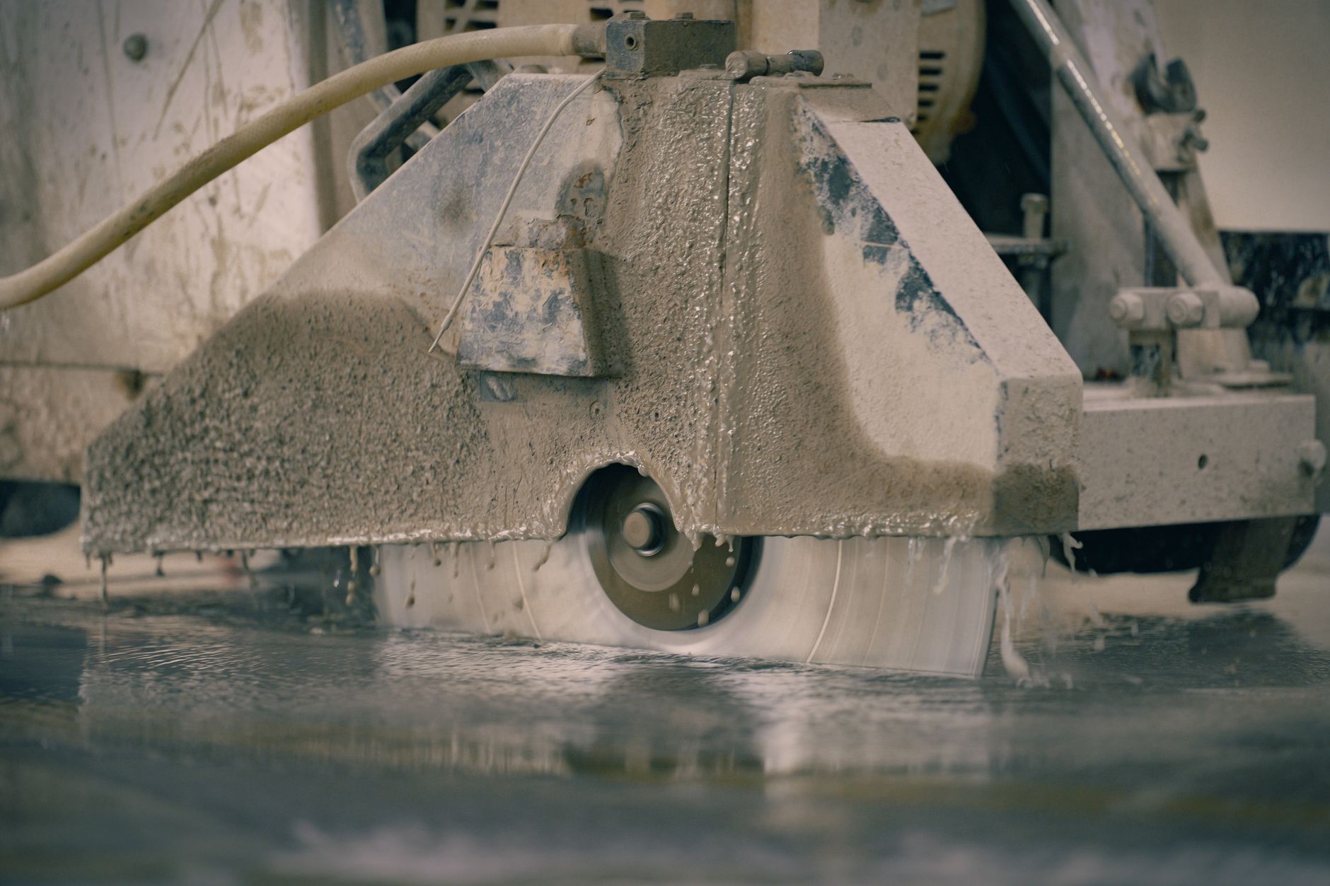 Wet cutting or grinding of stone with water suppression in a fabrication environment to control dust.