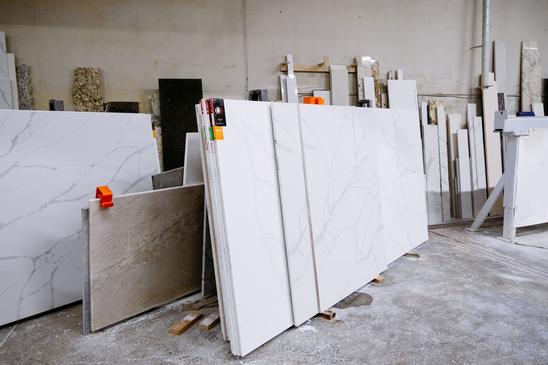 Finished stone pieces and slab racks organized in a fabrication shop, suggesting steadier flow and cleaner handoff work.